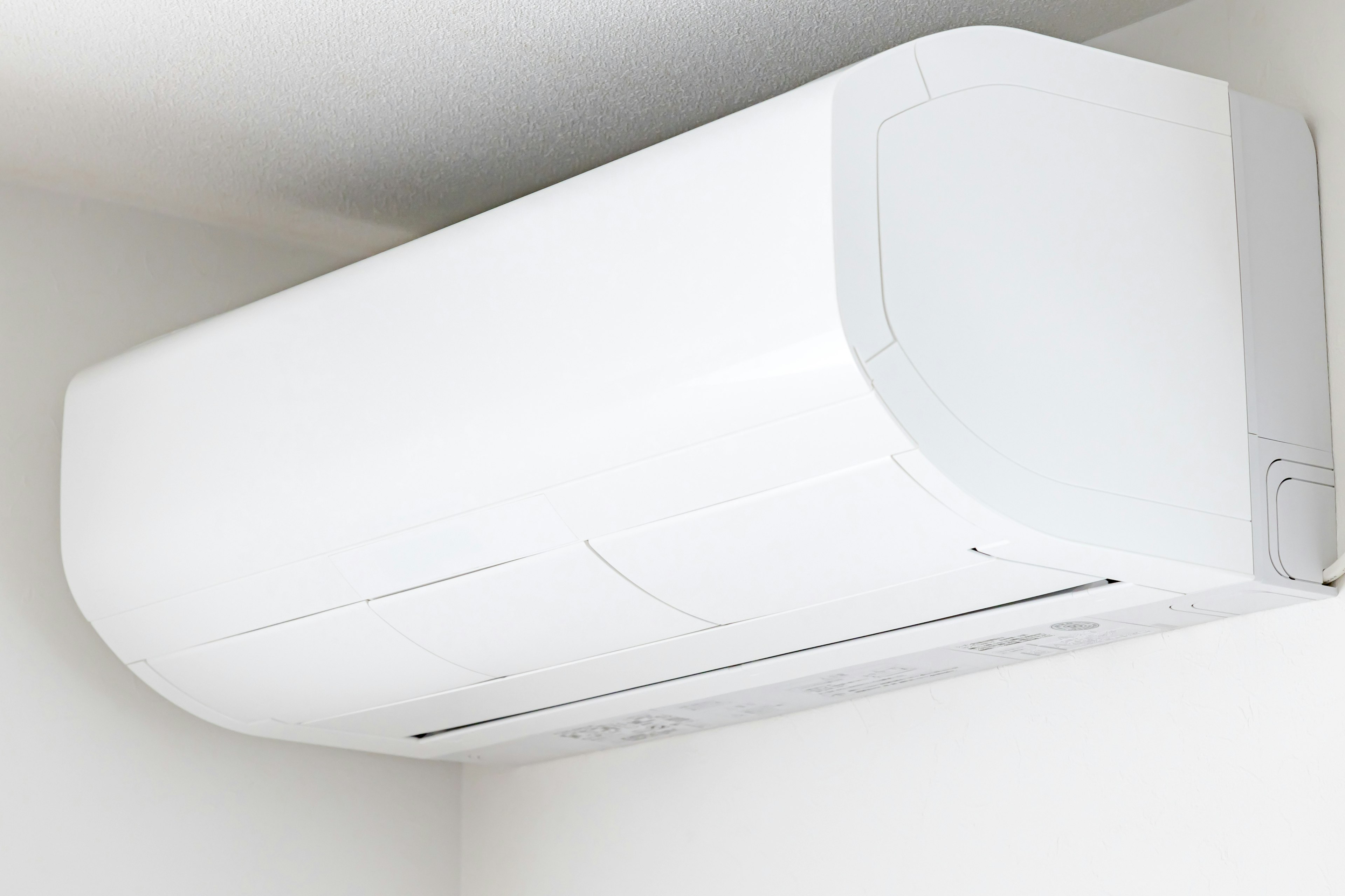 A white air conditioning unit mounted on a wall in a simple indoor setting