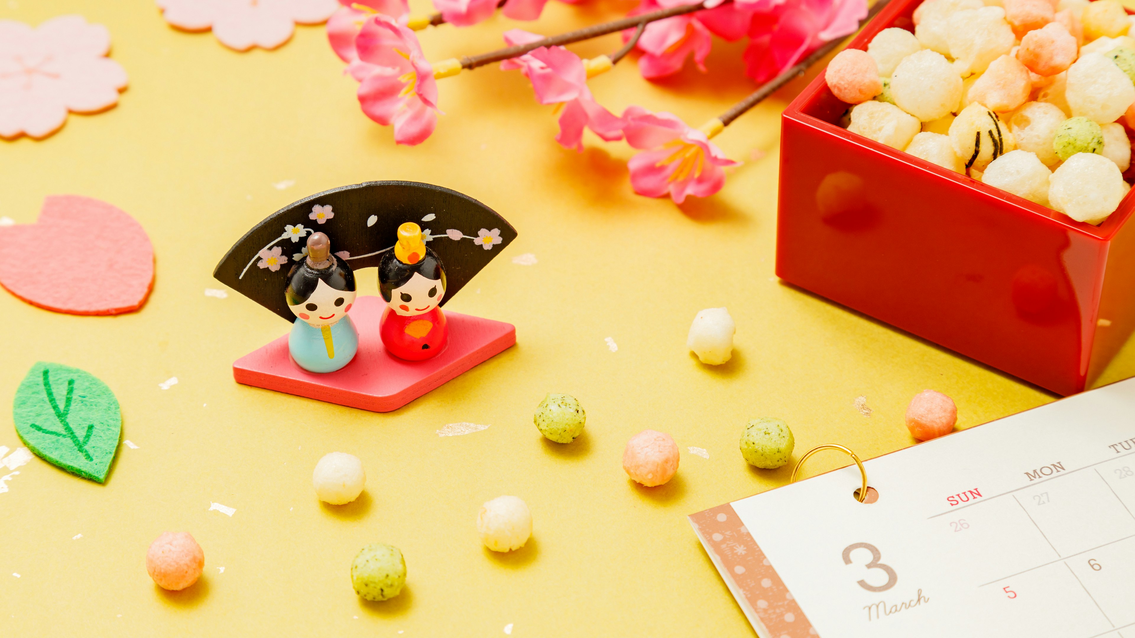 Hinamatsuri decoration with cherry blossom petals and colorful Japanese sweets scattered