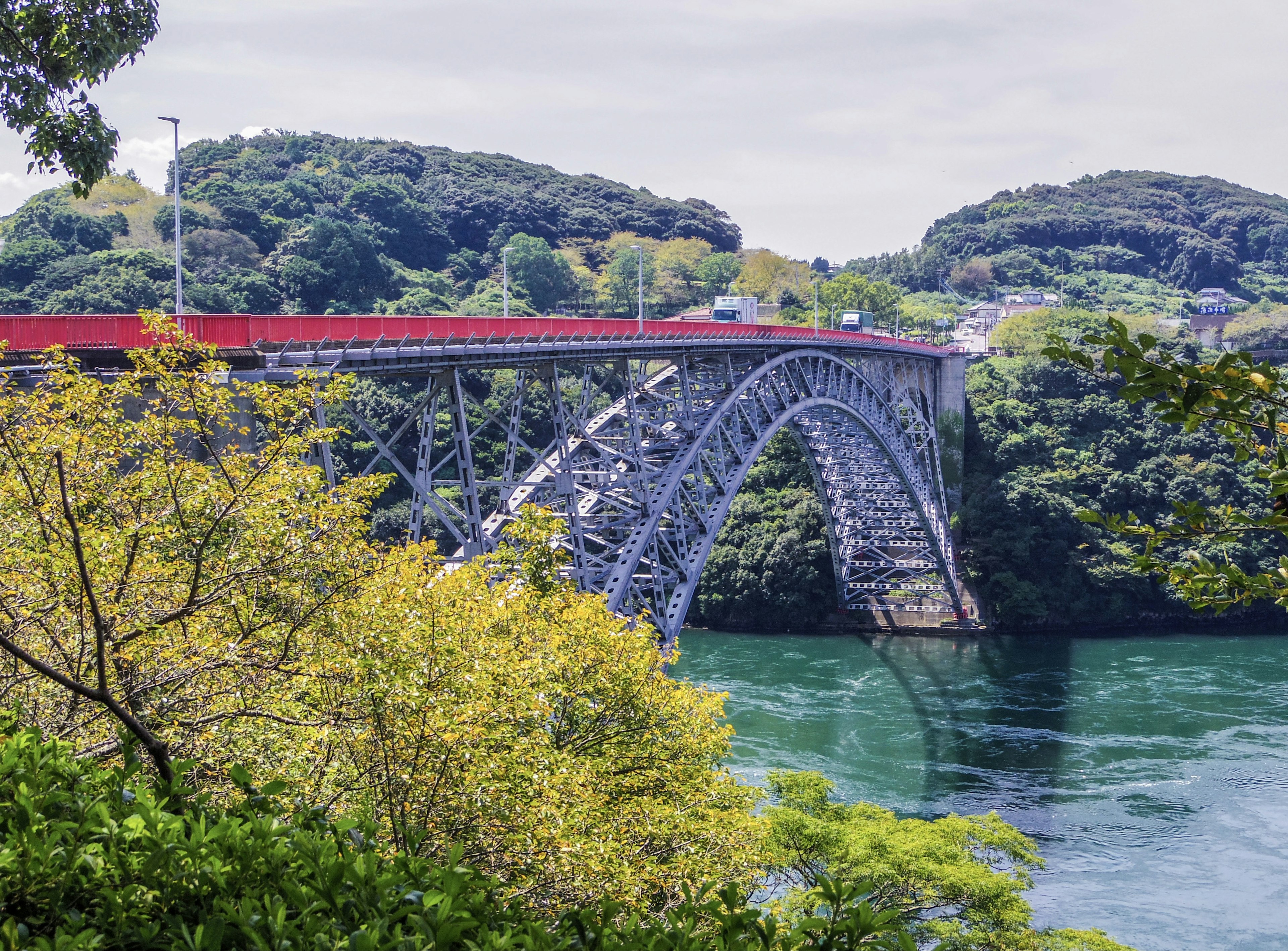 An arched bridge surrounded by greenery spanning over a body of water