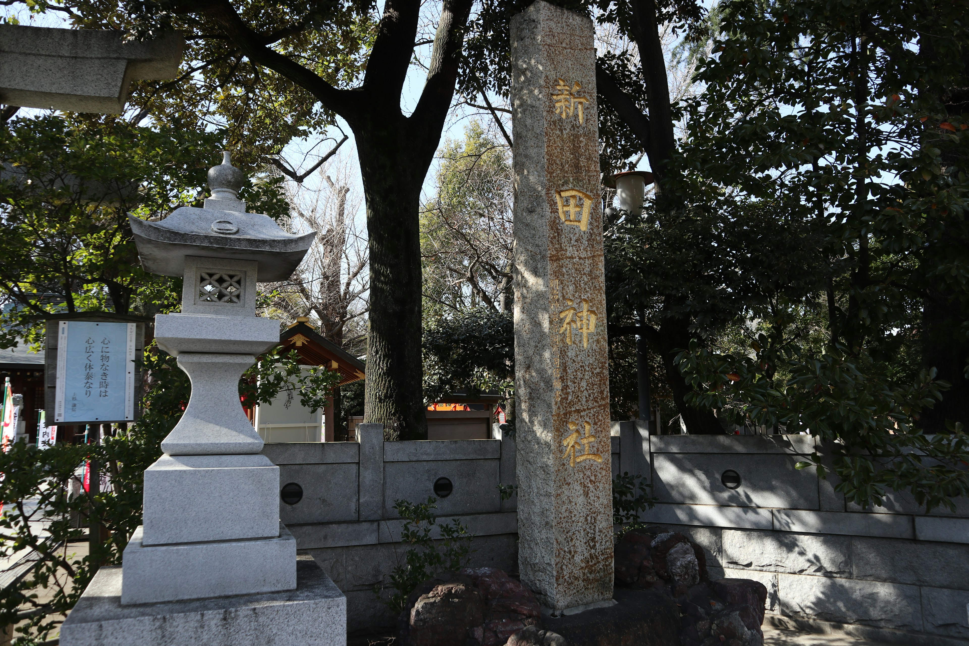 Scenic view of a shrine with a stone monument and lantern surrounded by green trees