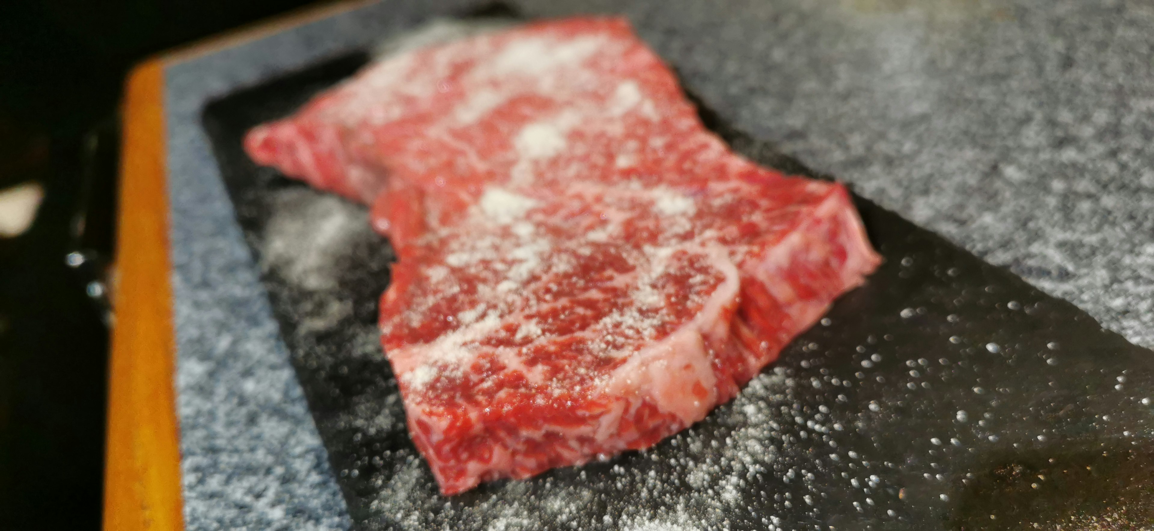 A piece of red meat on a black stone plate