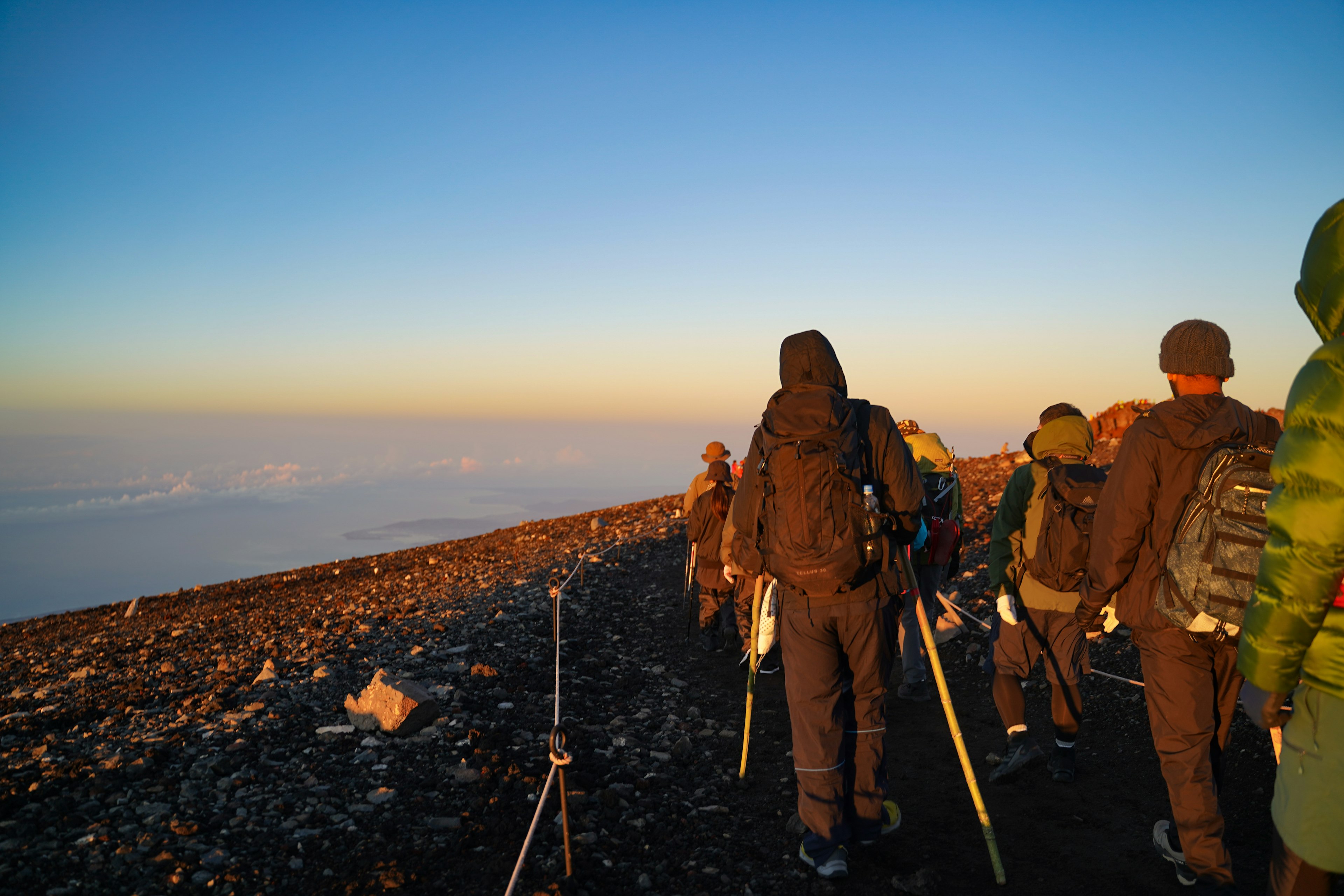 登山者が日の出を迎える山道を歩いている