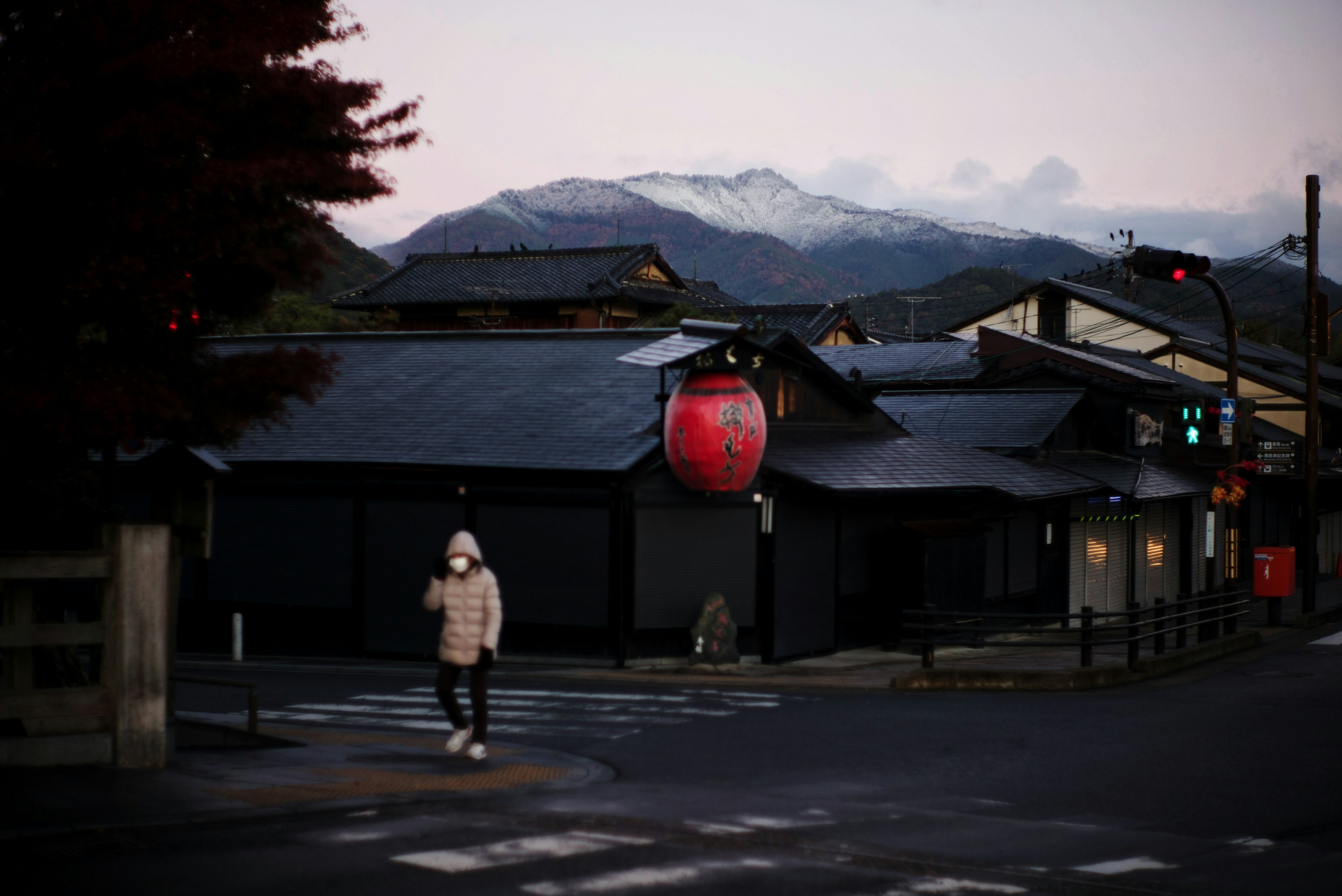 Quiet street corner with black buildings and red lanterns mountains in the background at dusk