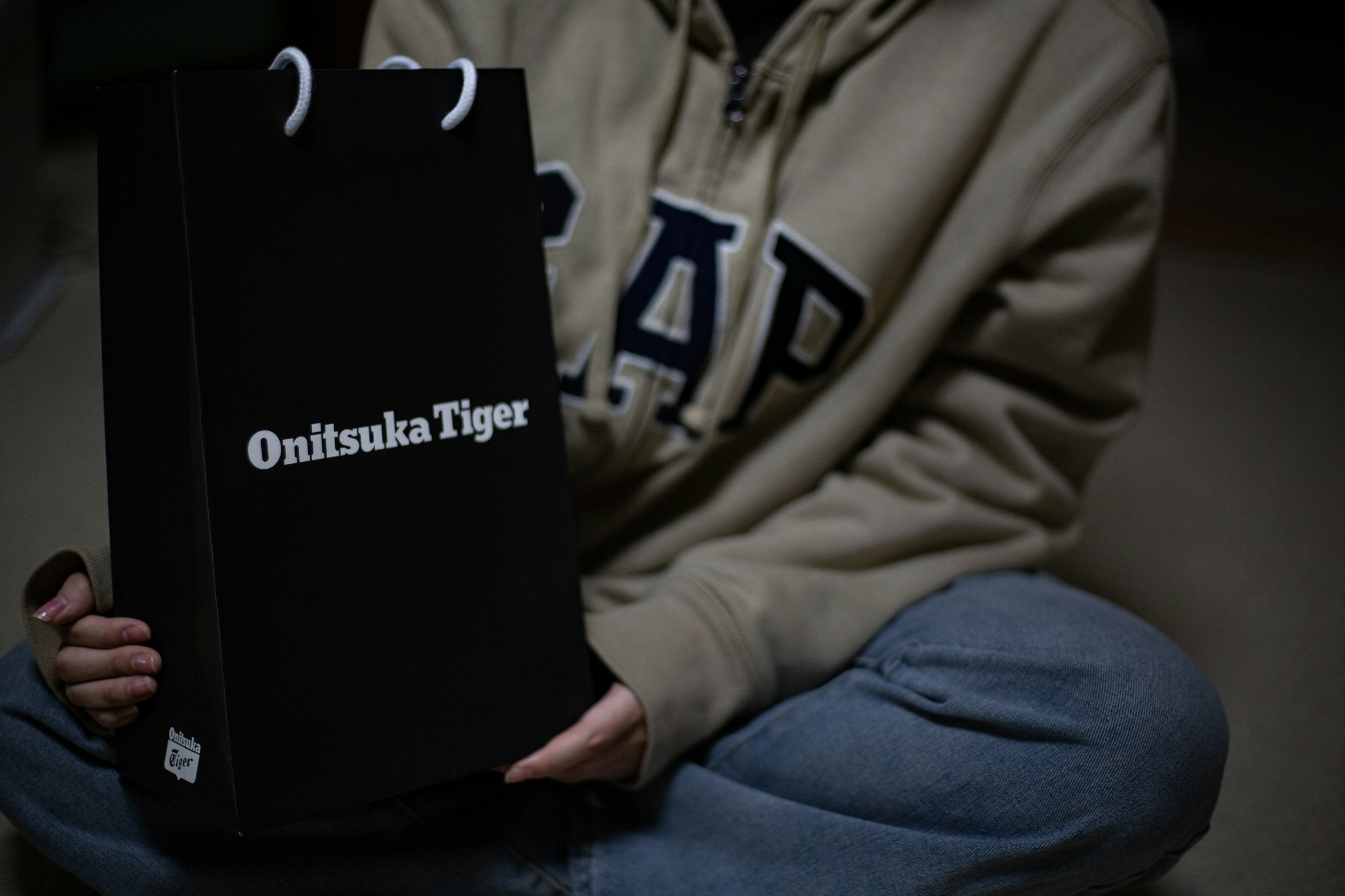 Person holding a black shopping bag from Onitsuka Tiger