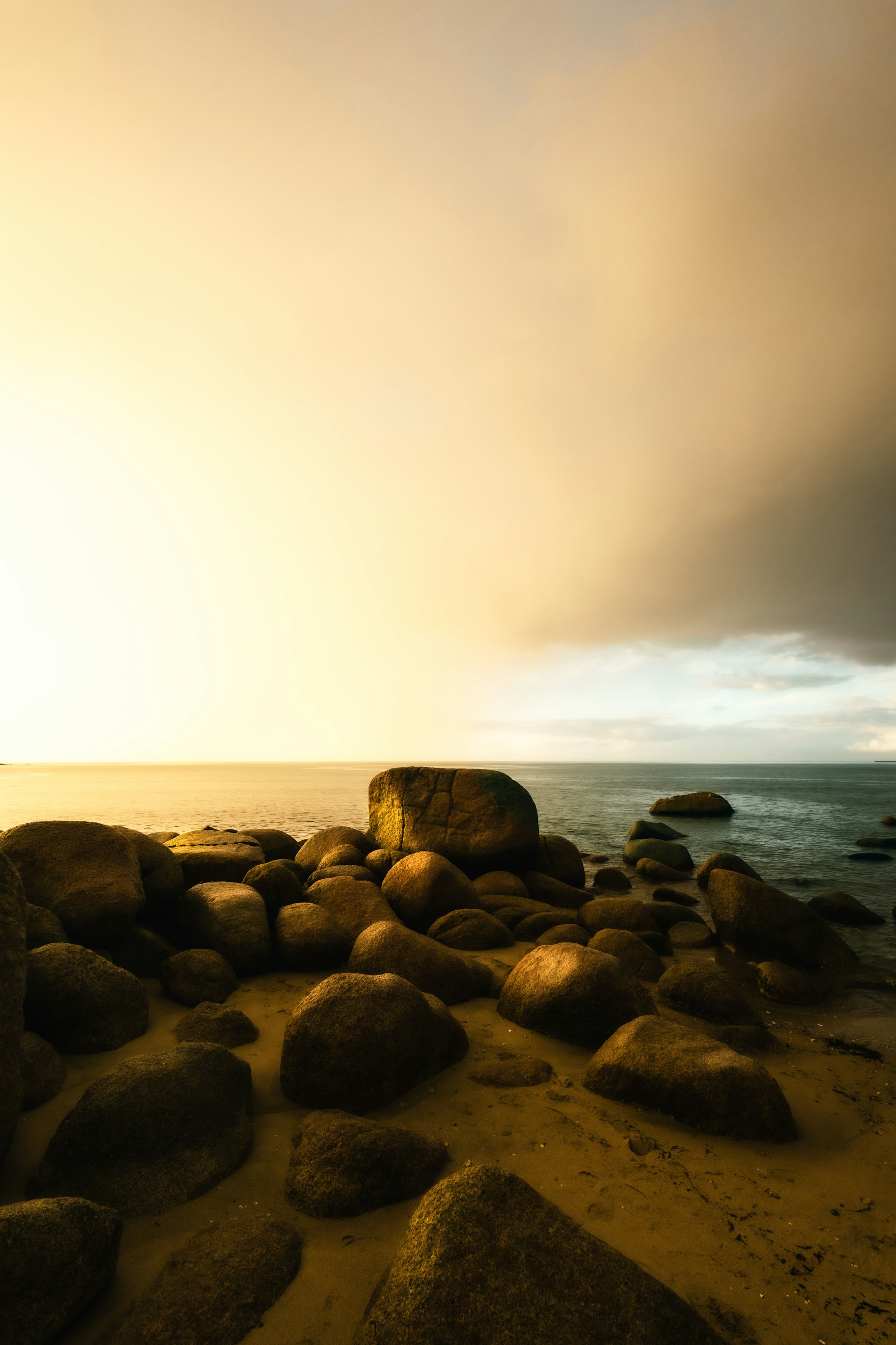 Coastal rocks and sandy beach scene with sunset sky hues