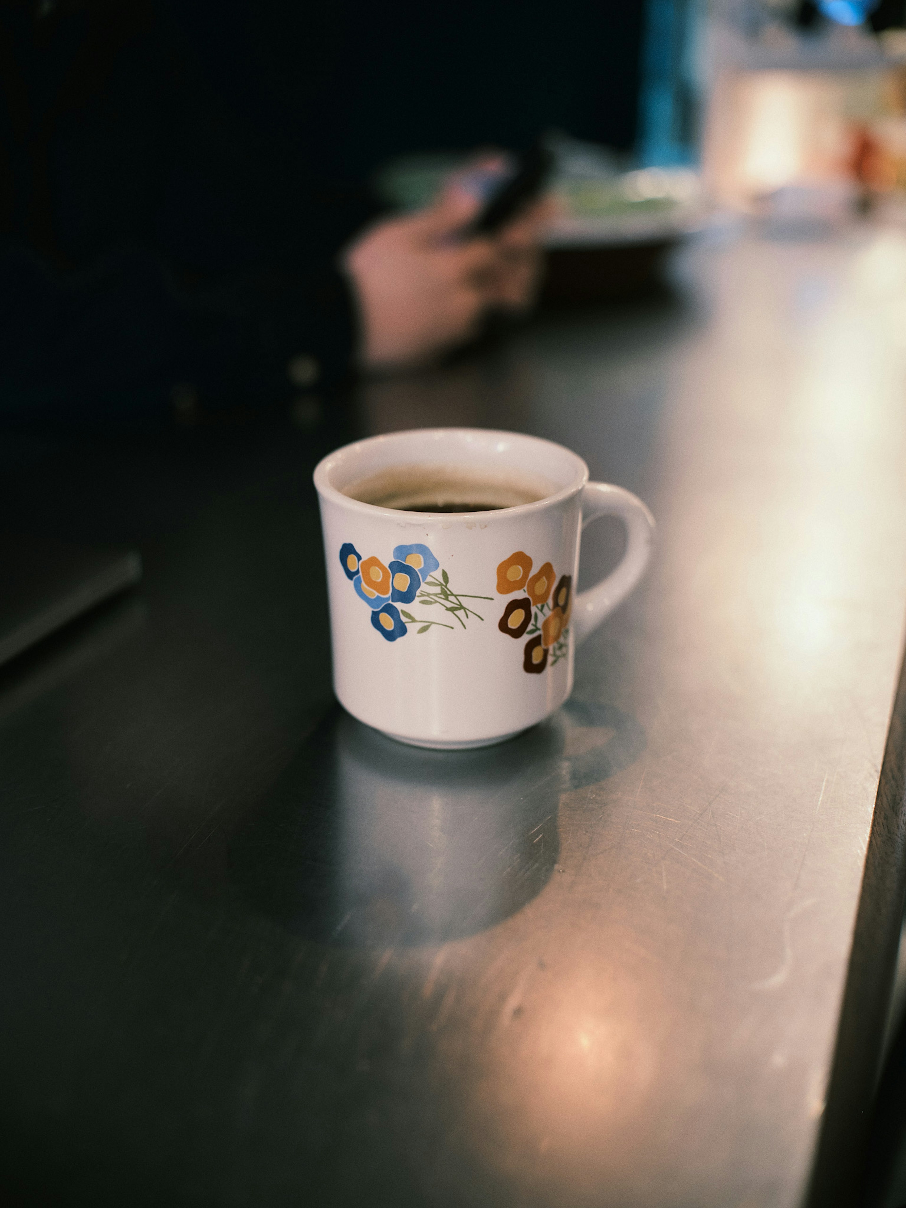 Tazza da caffè floreale colorata posata su un tavolo di metallo