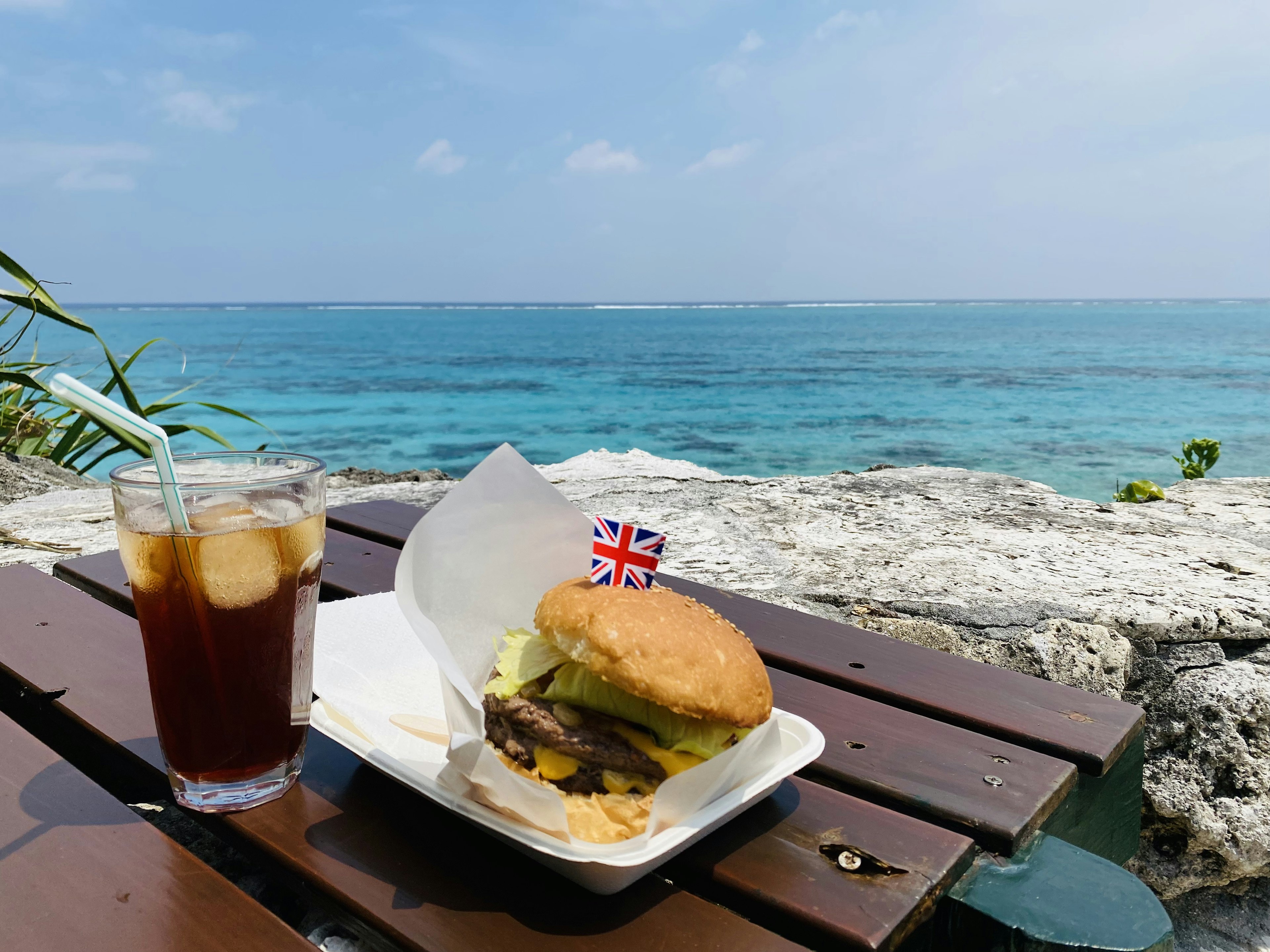 青い海を背景にしたハンバーガーとアイスティーの料理