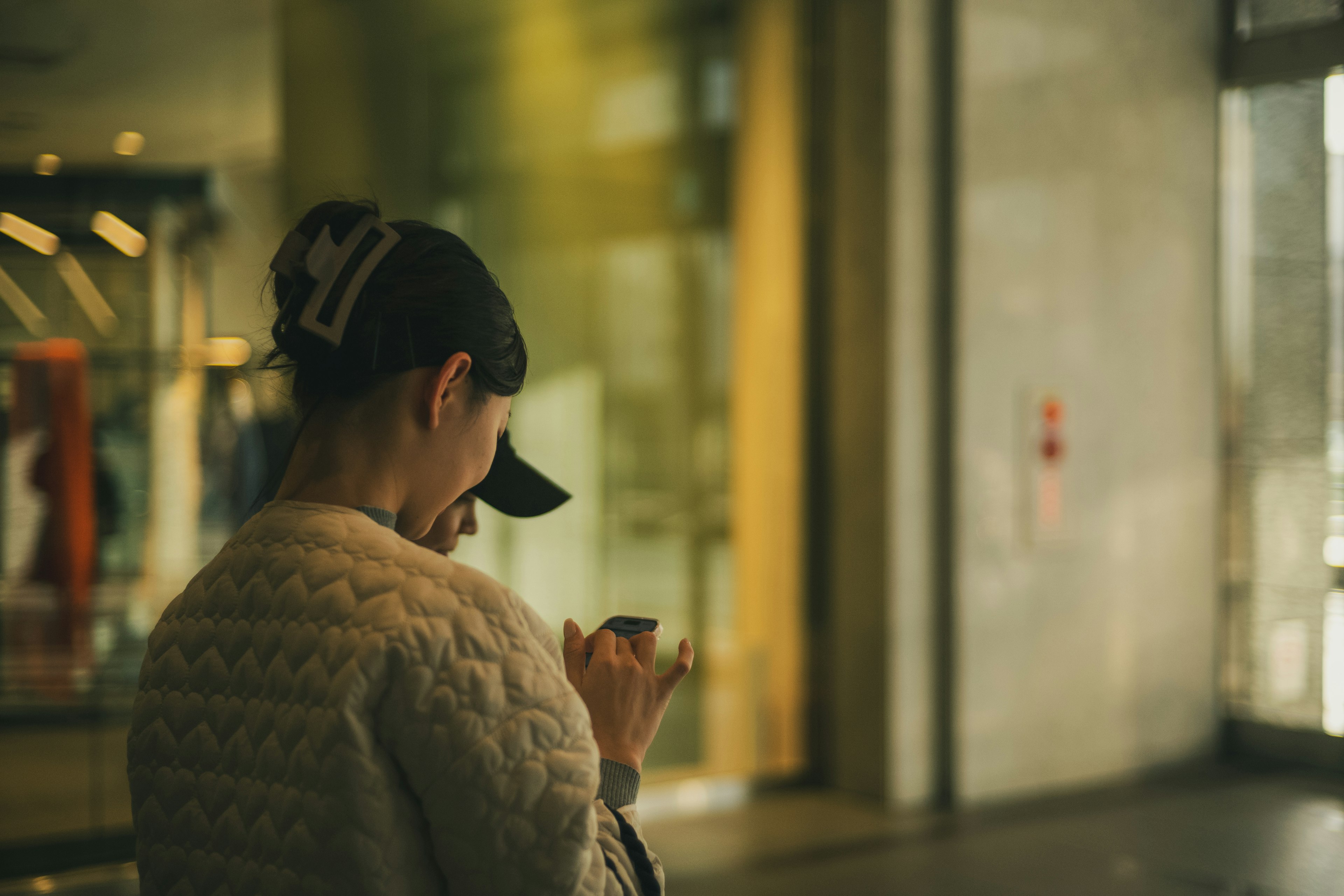 Foto de una mujer con gorra usando un teléfono inteligente de espaldas