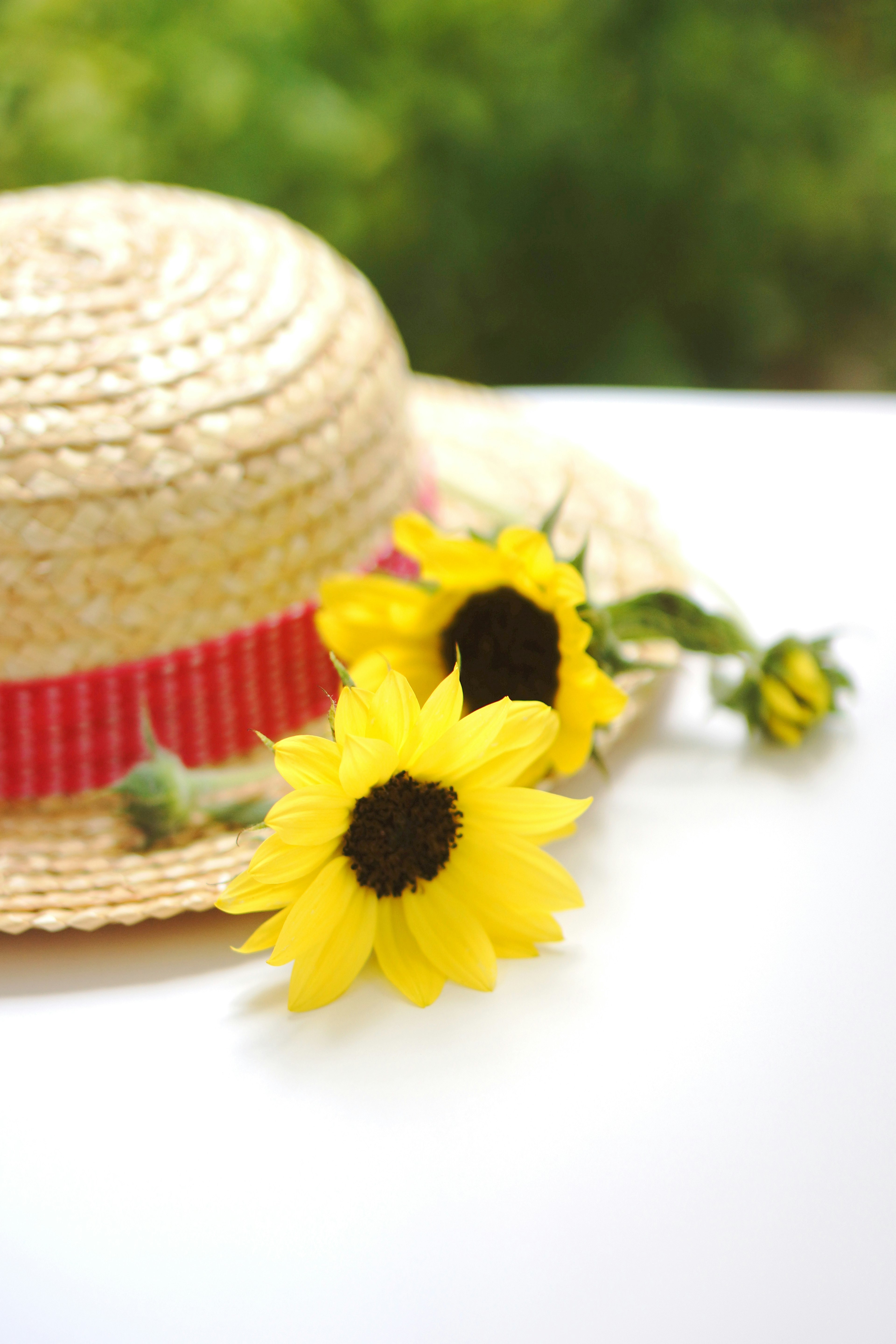 A straw hat adorned with yellow sunflowers and a red ribbon