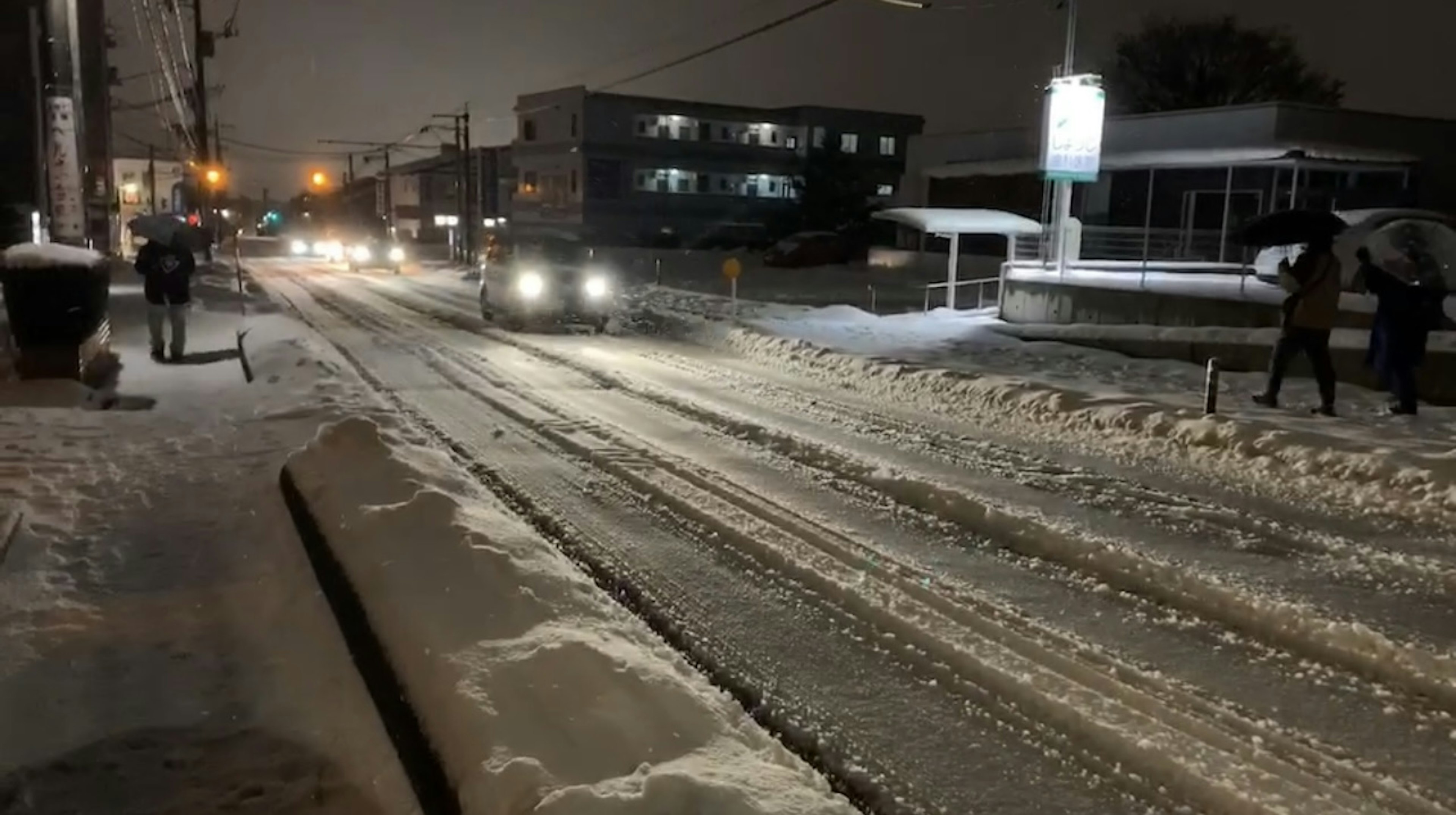 雪夜場景，汽車的車頭燈照亮雪路