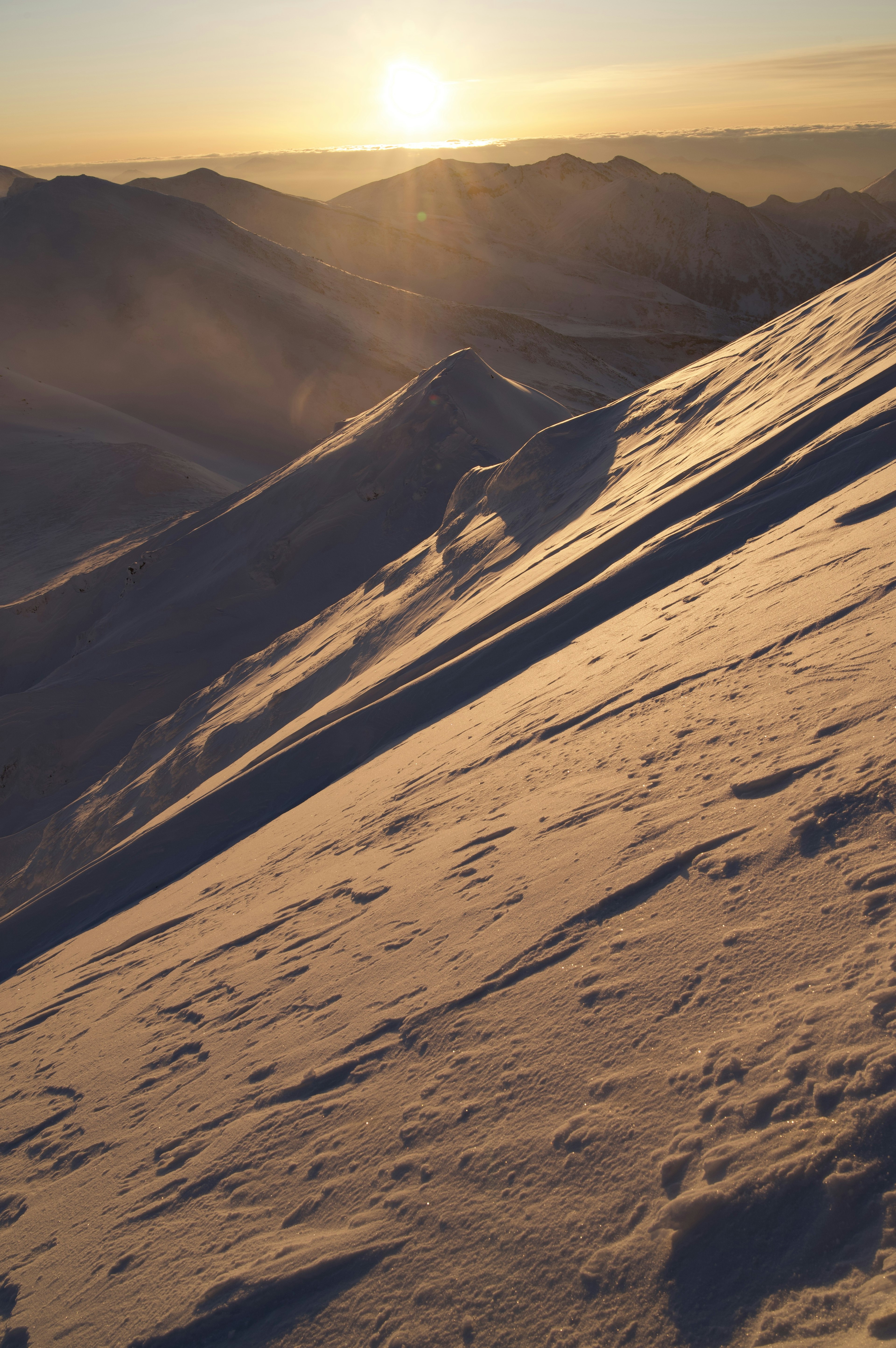 Pendiente de montaña cubierta de nieve con luz de atardecer