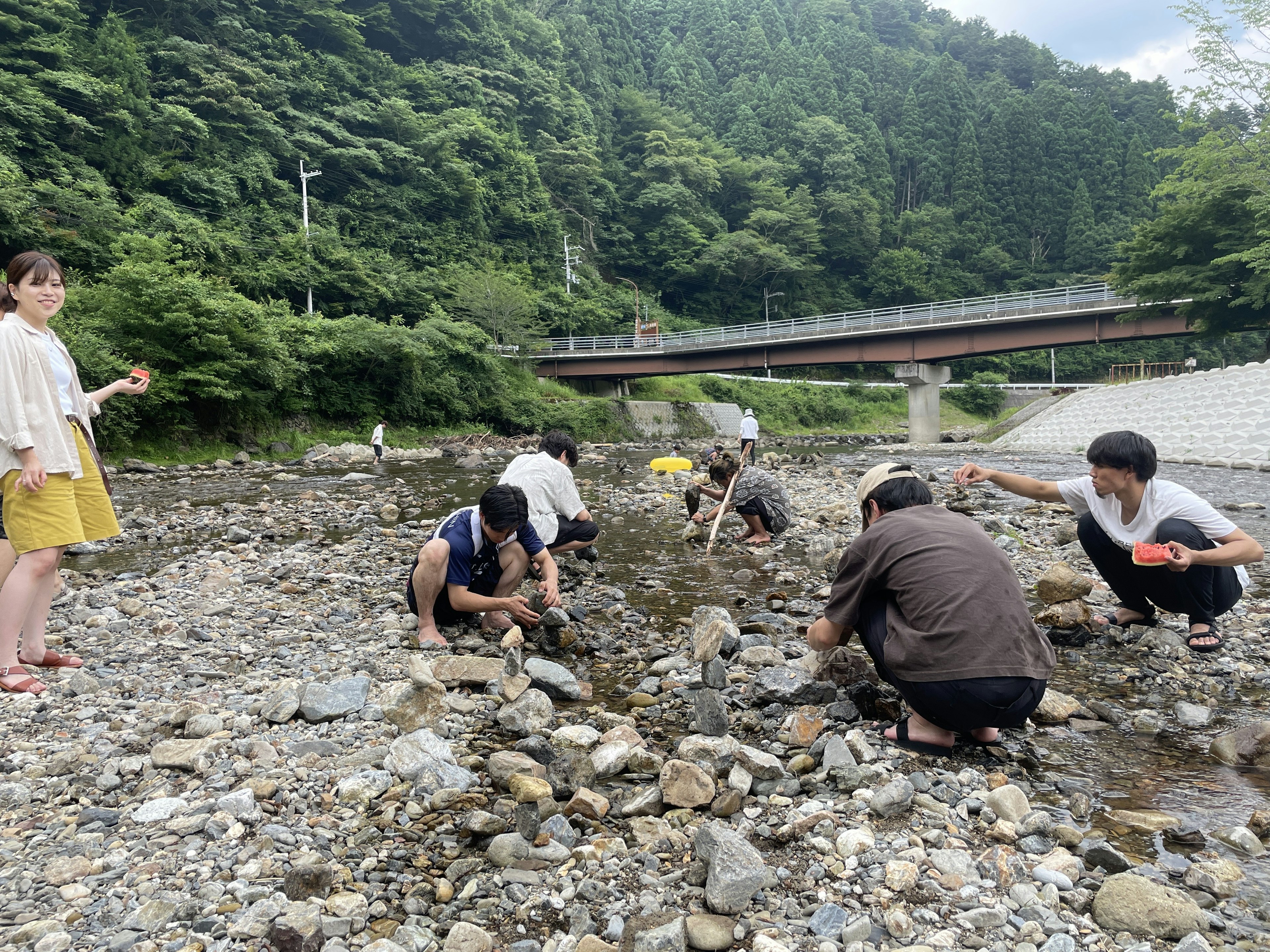 Orang-orang mencari batu di sungai dengan latar belakang hijau