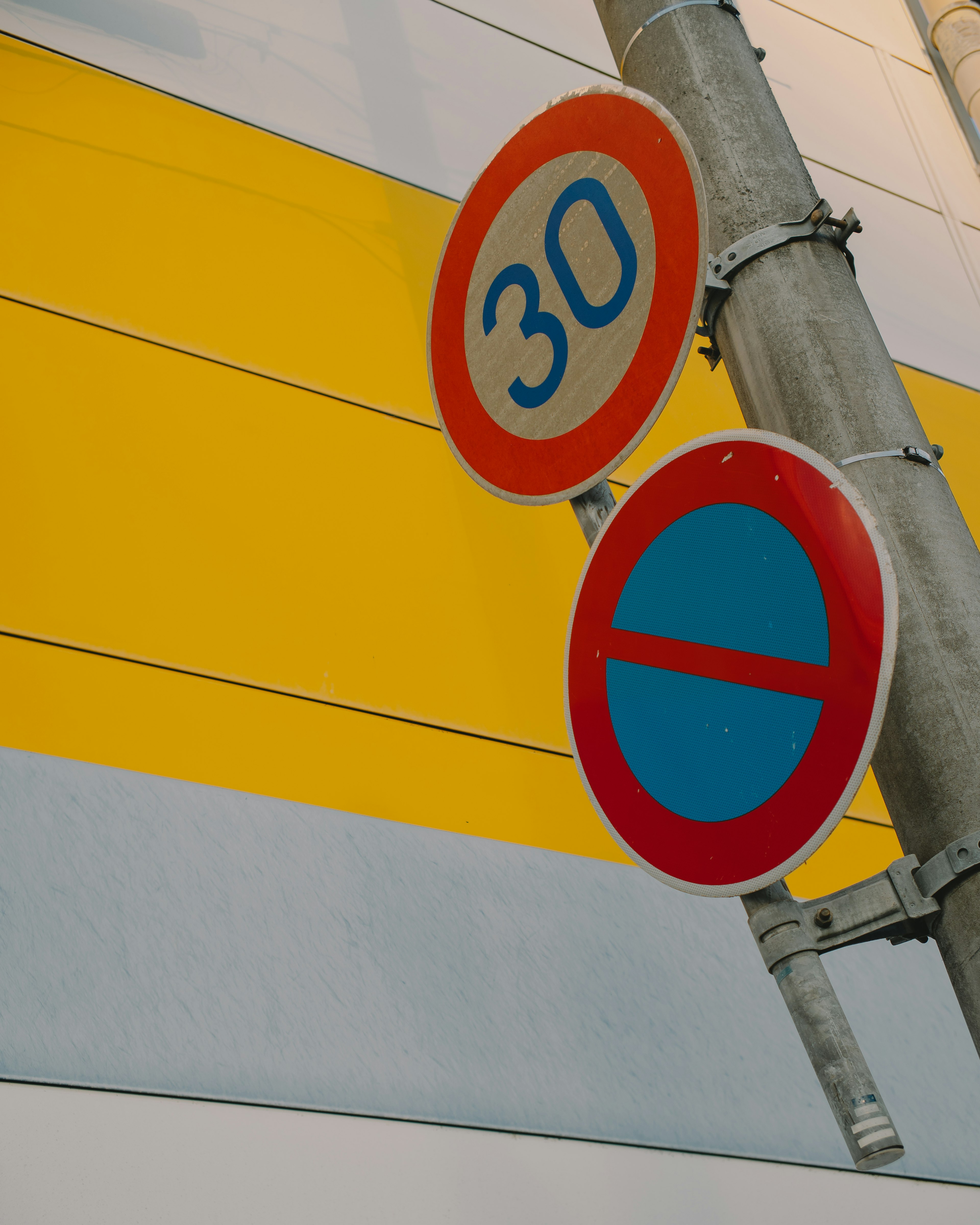 Señal de límite de velocidad 30 y señal de no estacionar en una pared amarilla