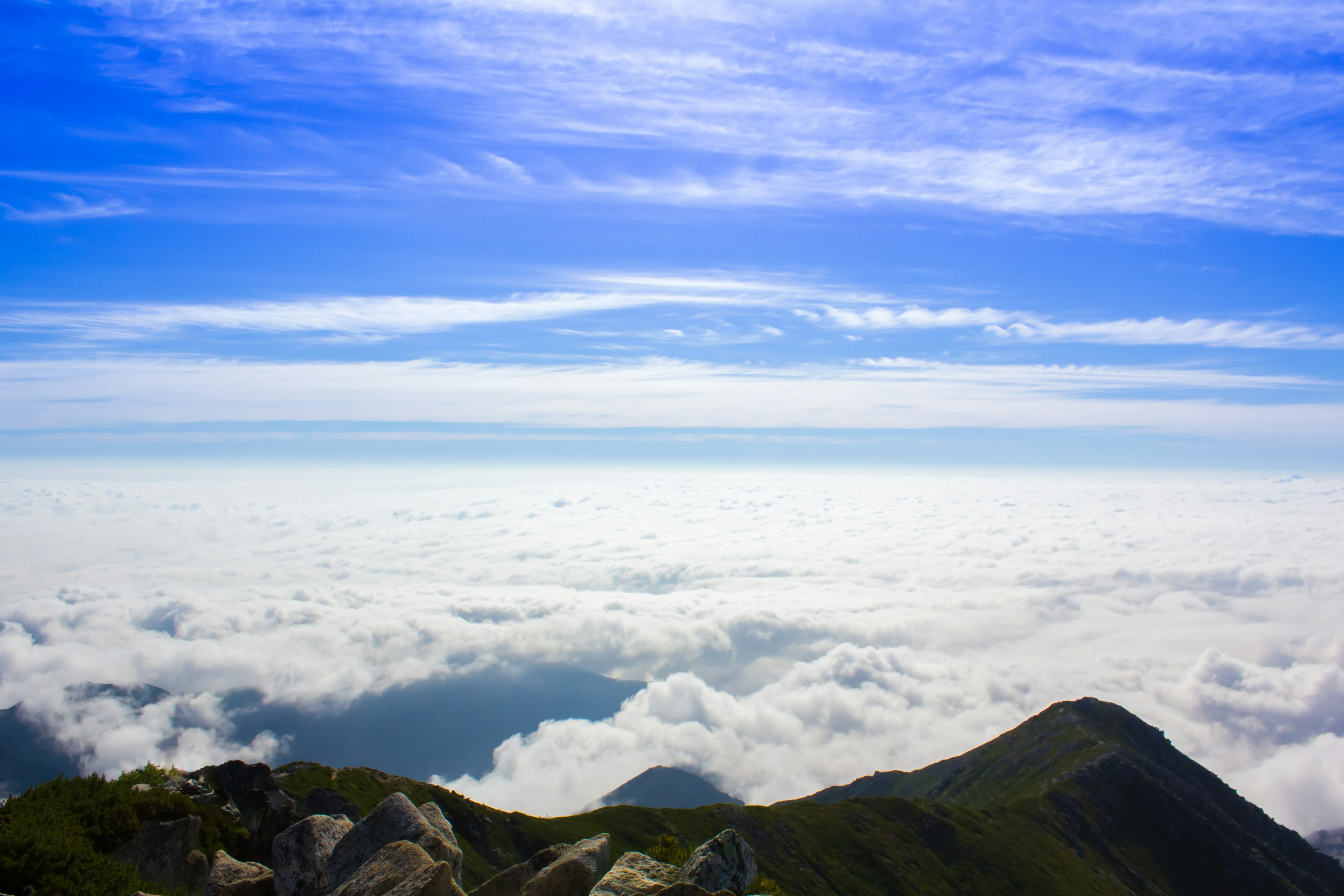 Pemandangan gunung dikelilingi lautan awan dan langit biru