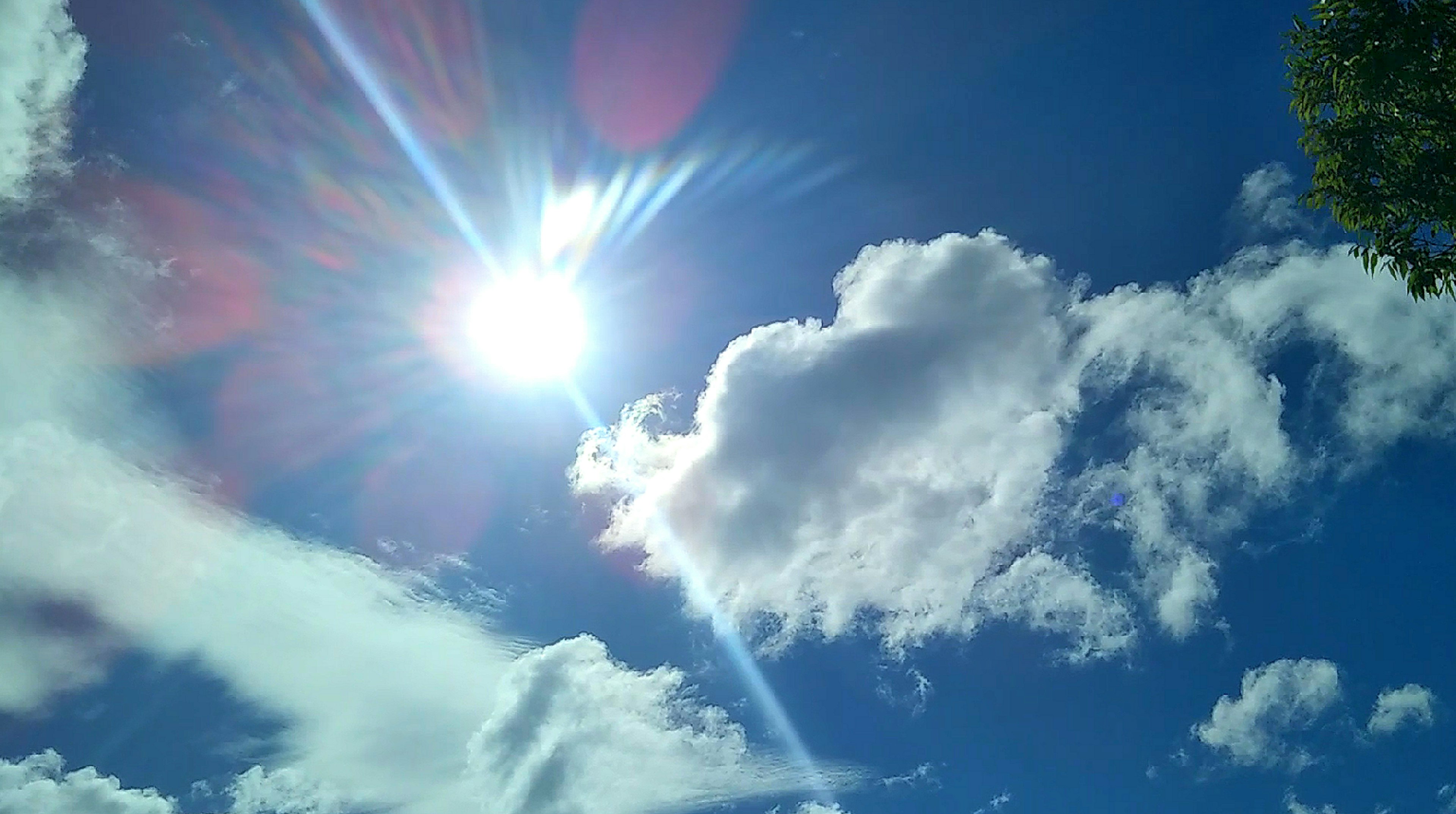 Bright sunlight shining through fluffy clouds in a blue sky