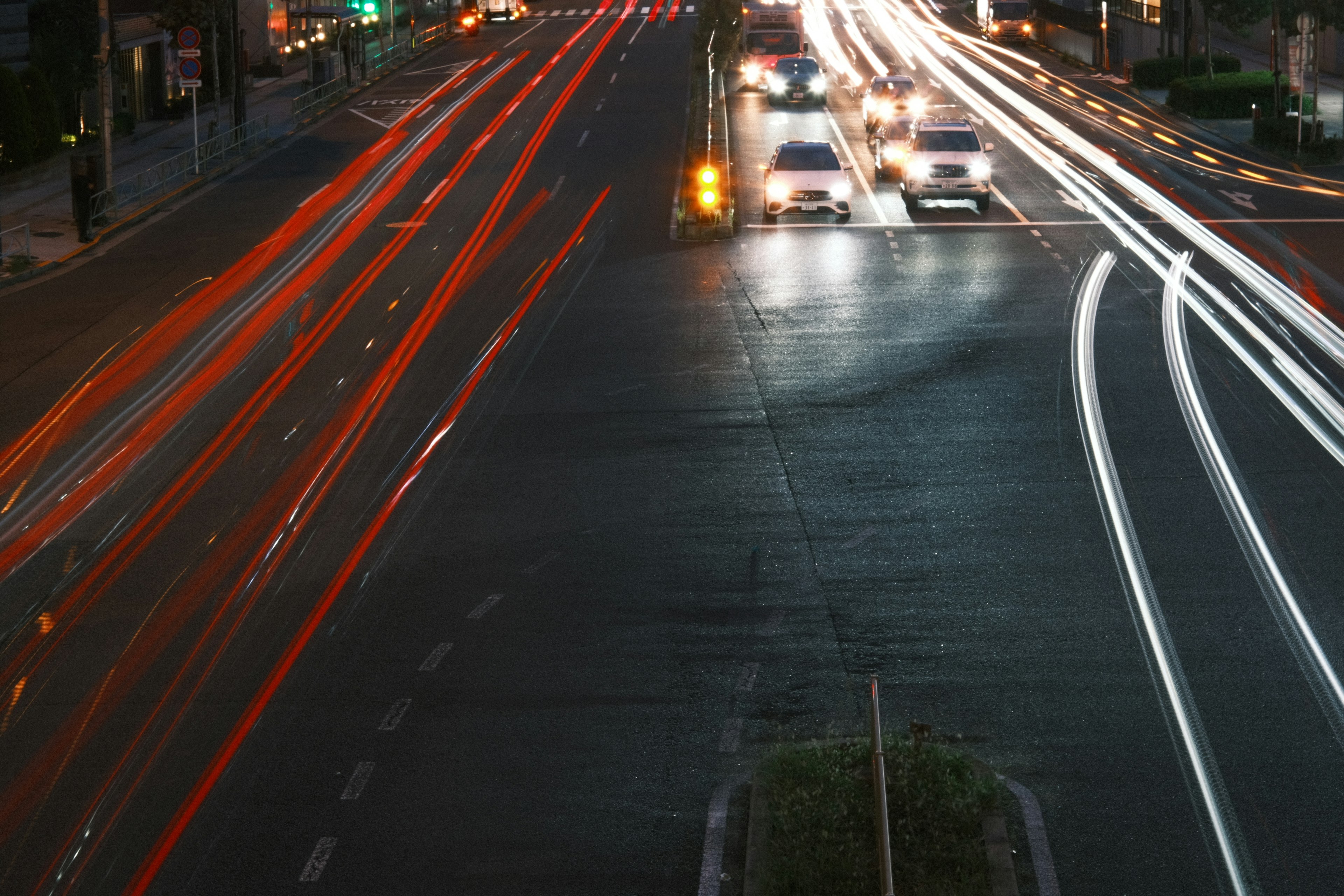 Intersección nocturna con estelas de luz de coches en movimiento