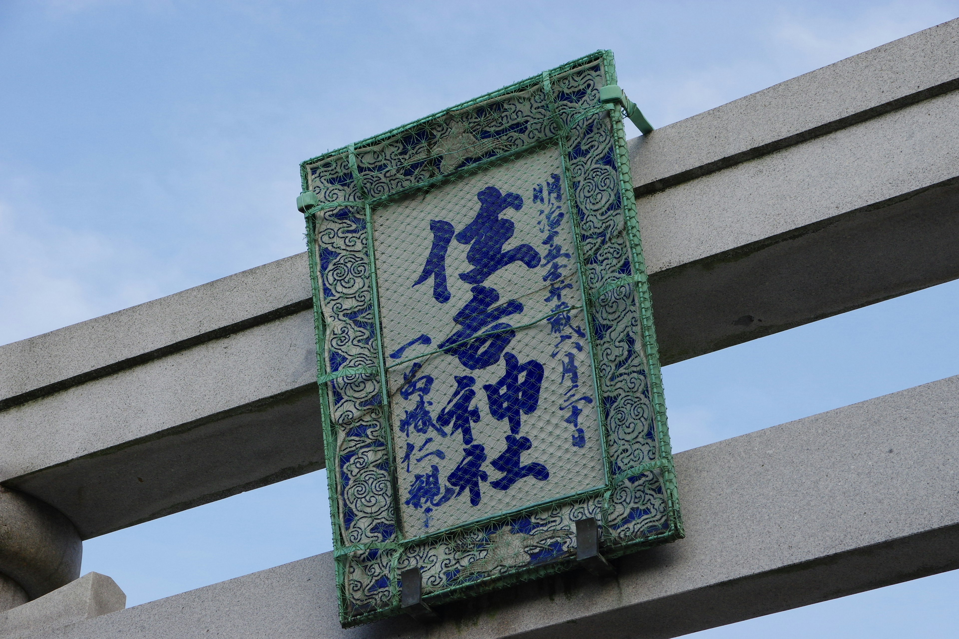 Papan gerbang kuil dengan tulisan biru di bawah langit biru