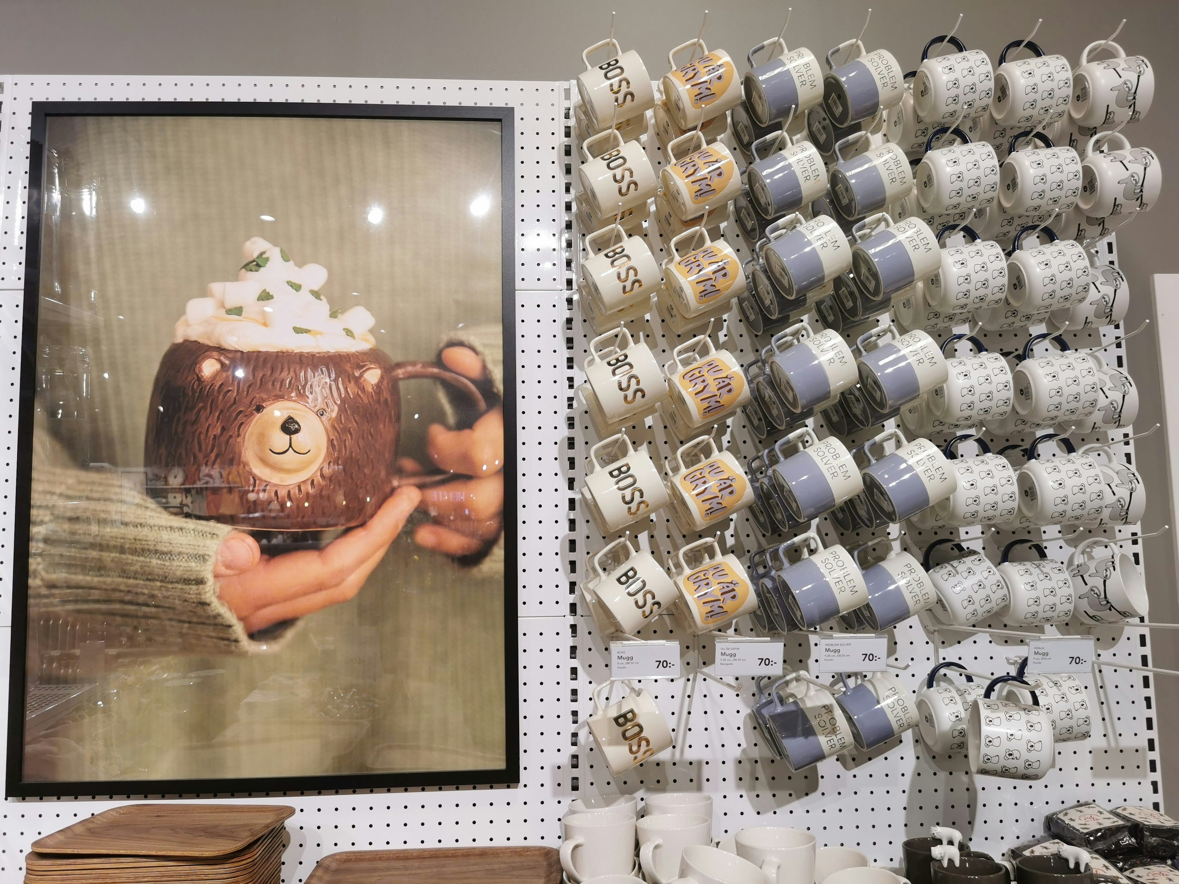 A cozy display featuring a bear mug and various patterned mugs on a wall