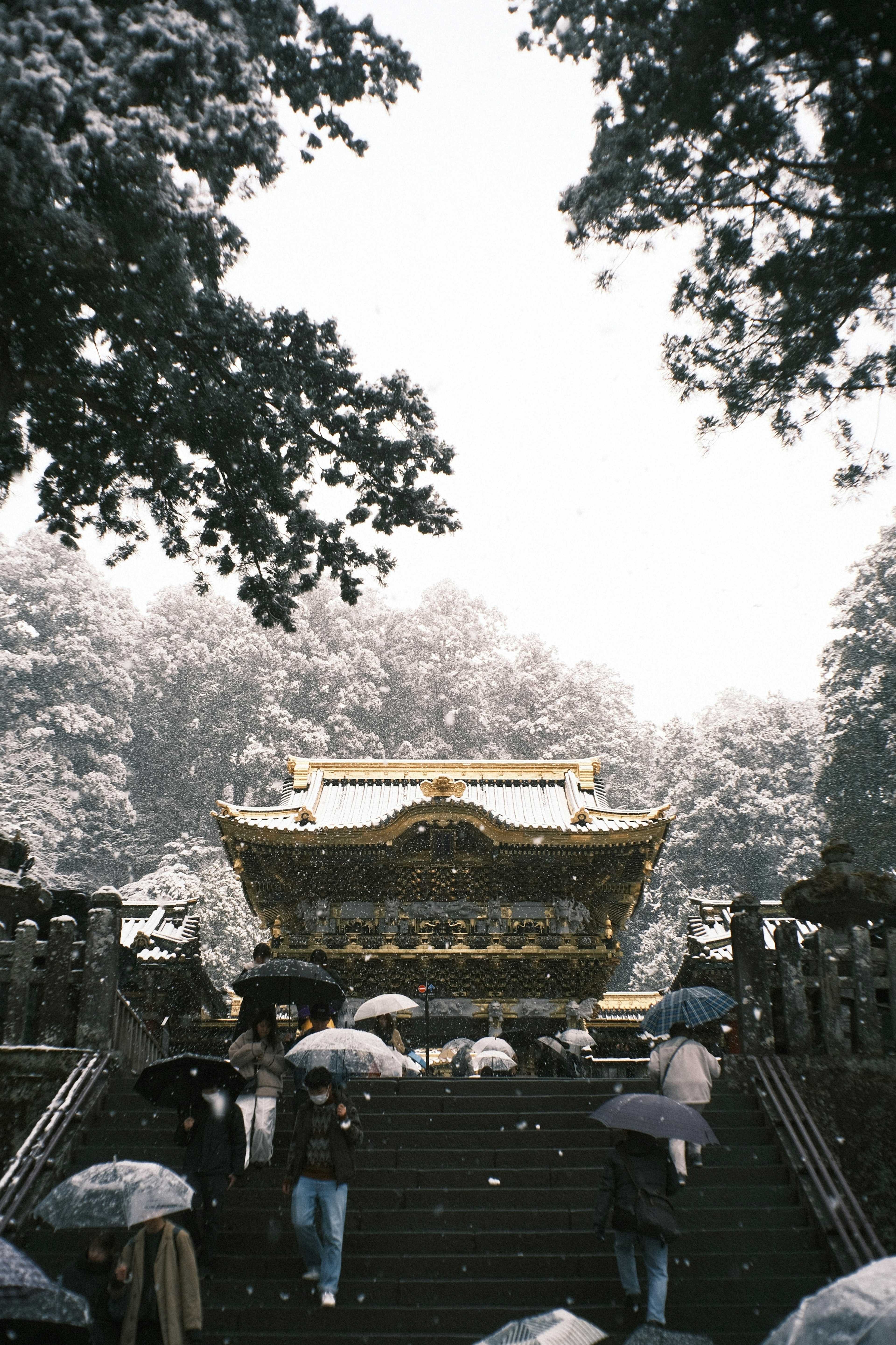 雪の中の神社の建物と傘を持つ人々