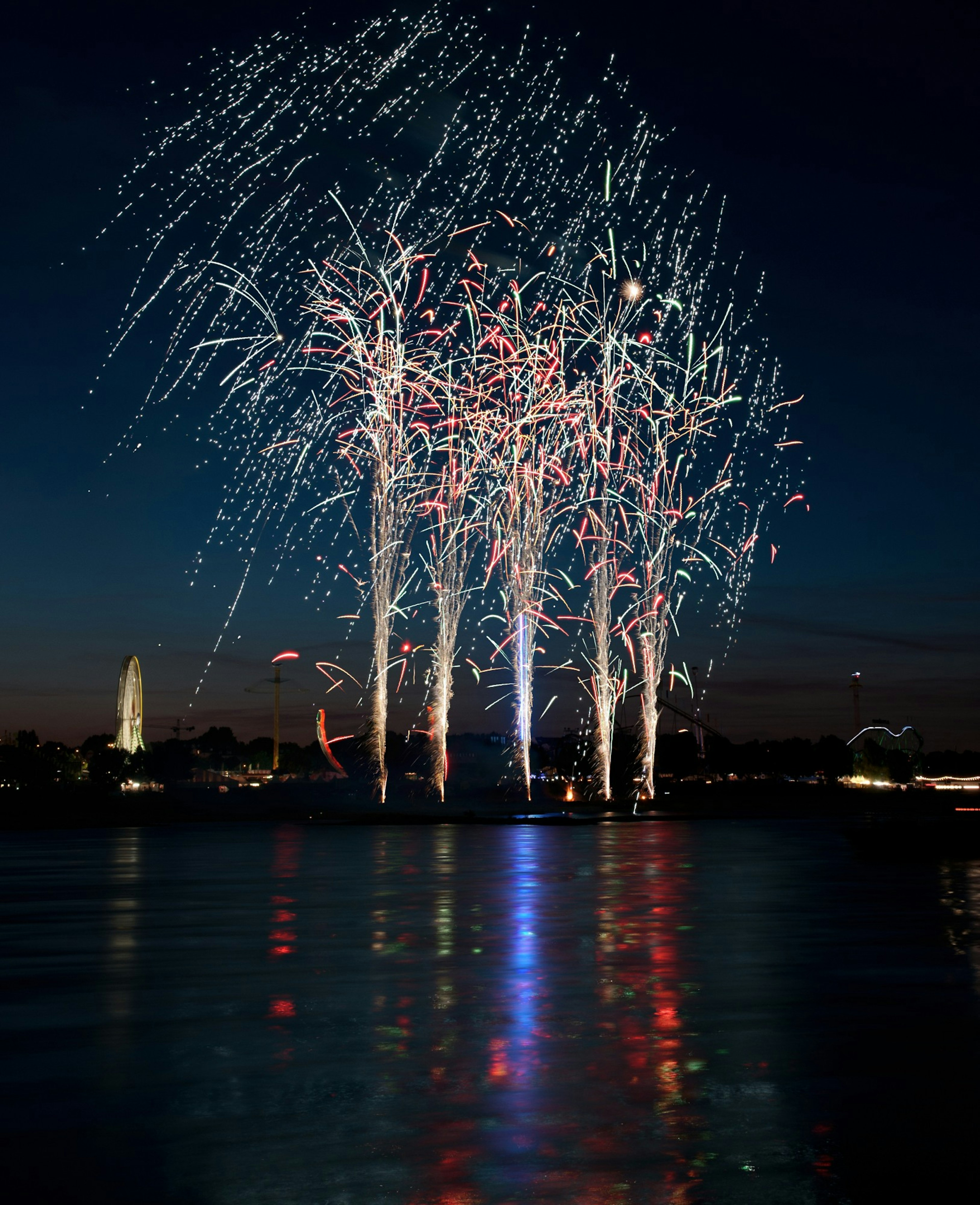 Bella scena di fuochi d'artificio che illuminano il cielo notturno riflesso sull'acqua