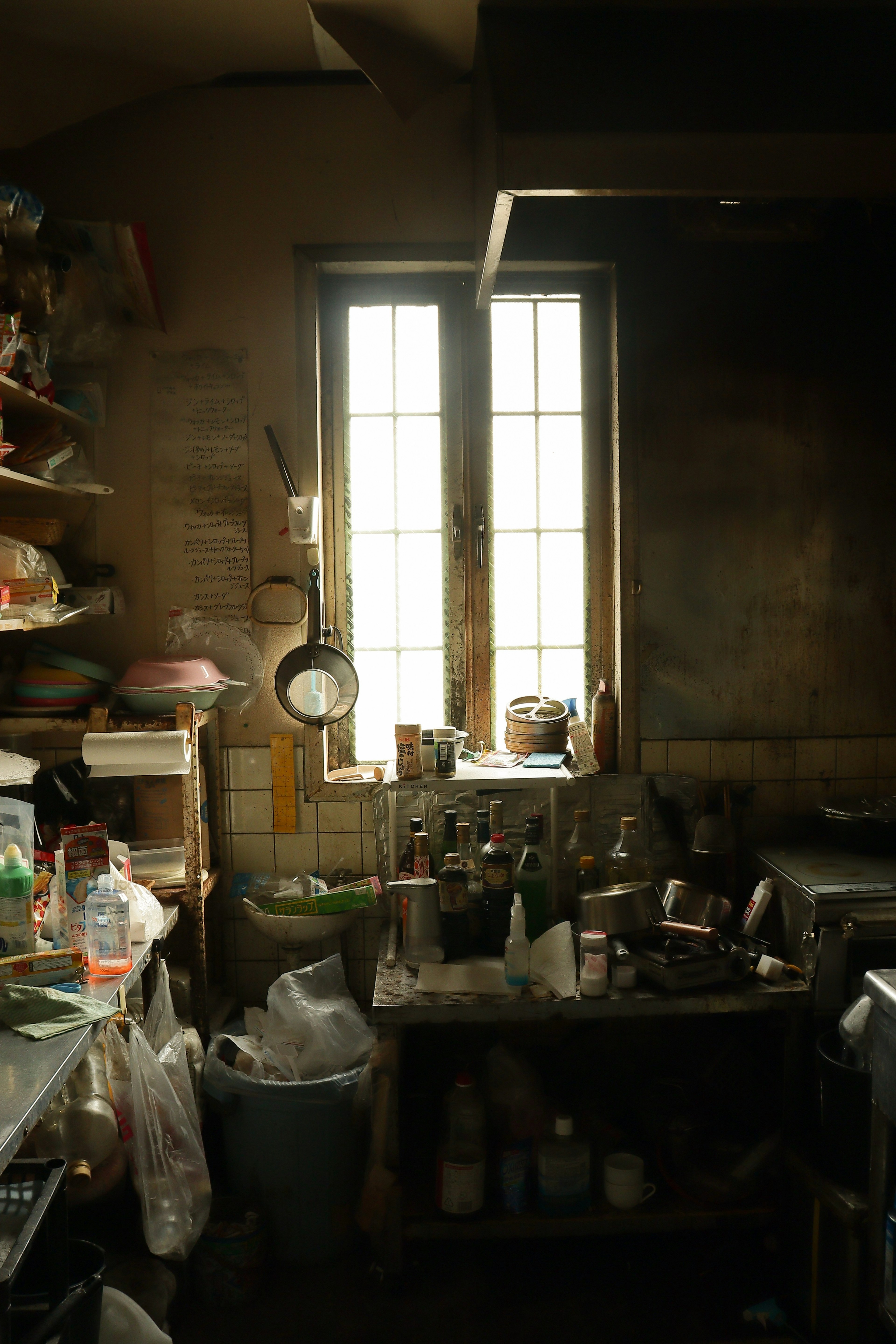 Espacio de trabajo desordenado con estantes y una ventana en una habitación oscura