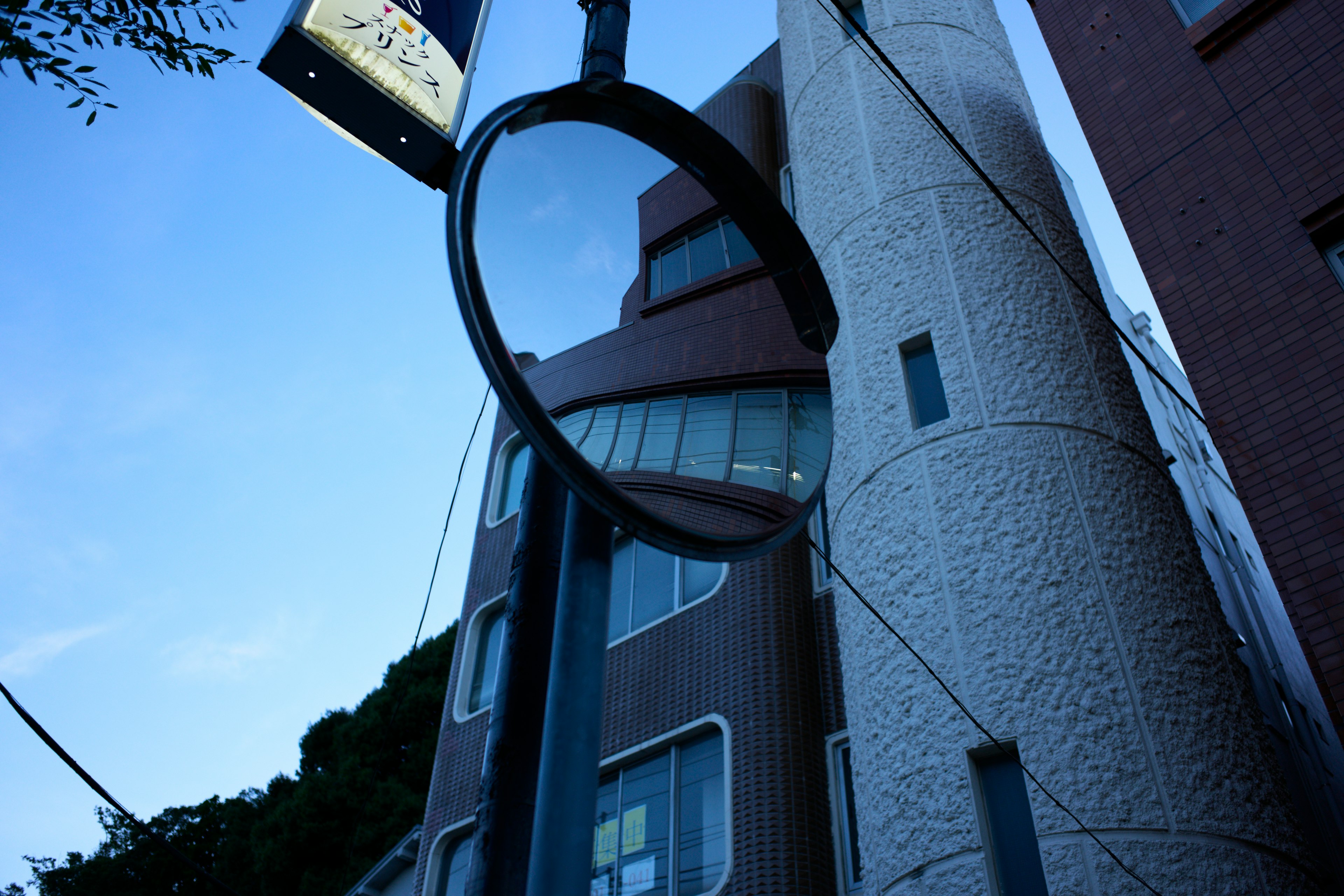 Straßenspiegel, der ein Betongebäude unter blauem Himmel reflektiert