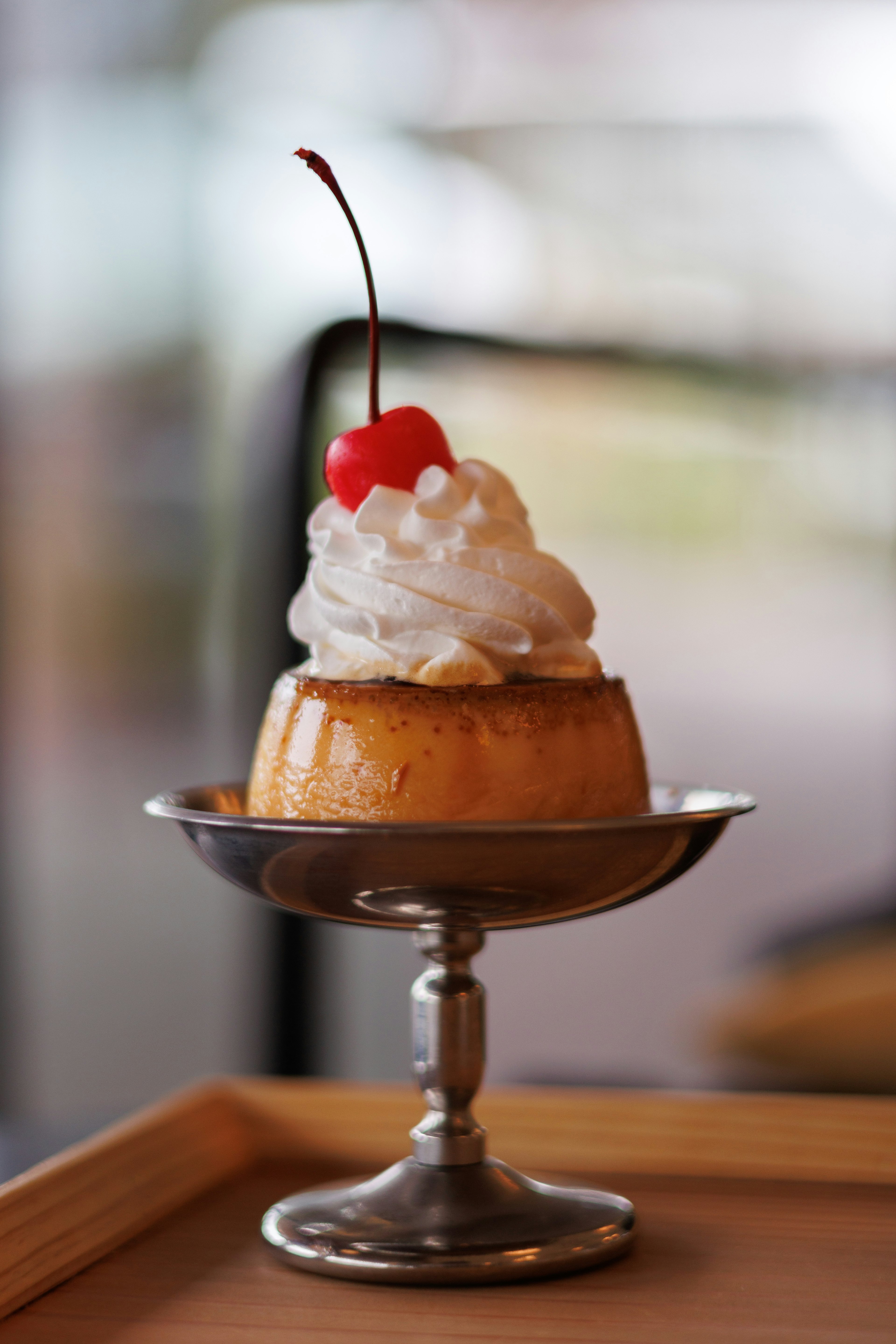 Postre con flan cubierto de crema batida y una cereza