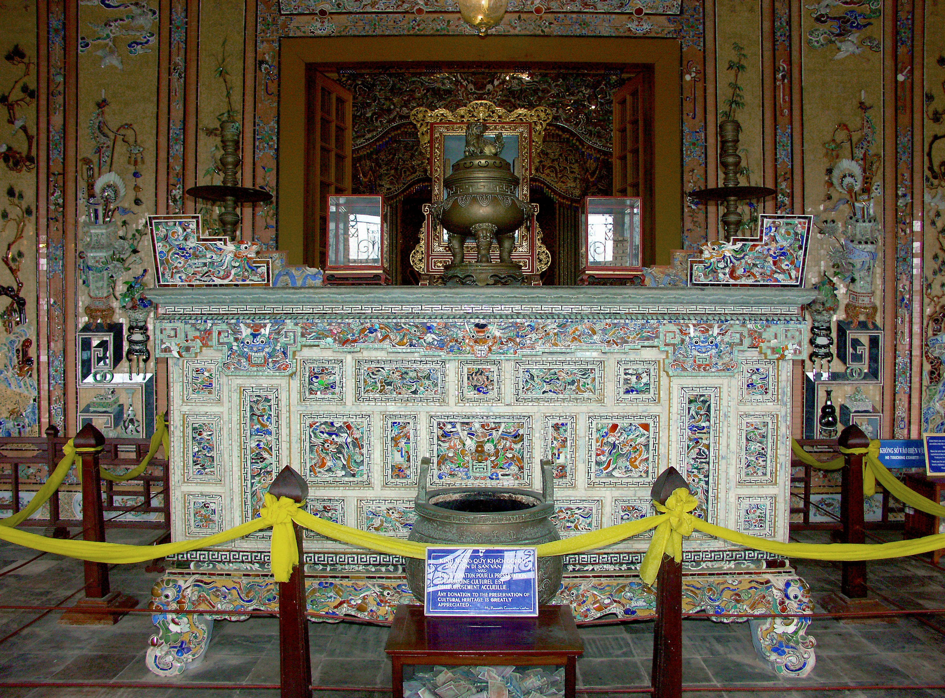 Altar tradicional con intrincadas decoraciones y un recipiente de bronce en el centro