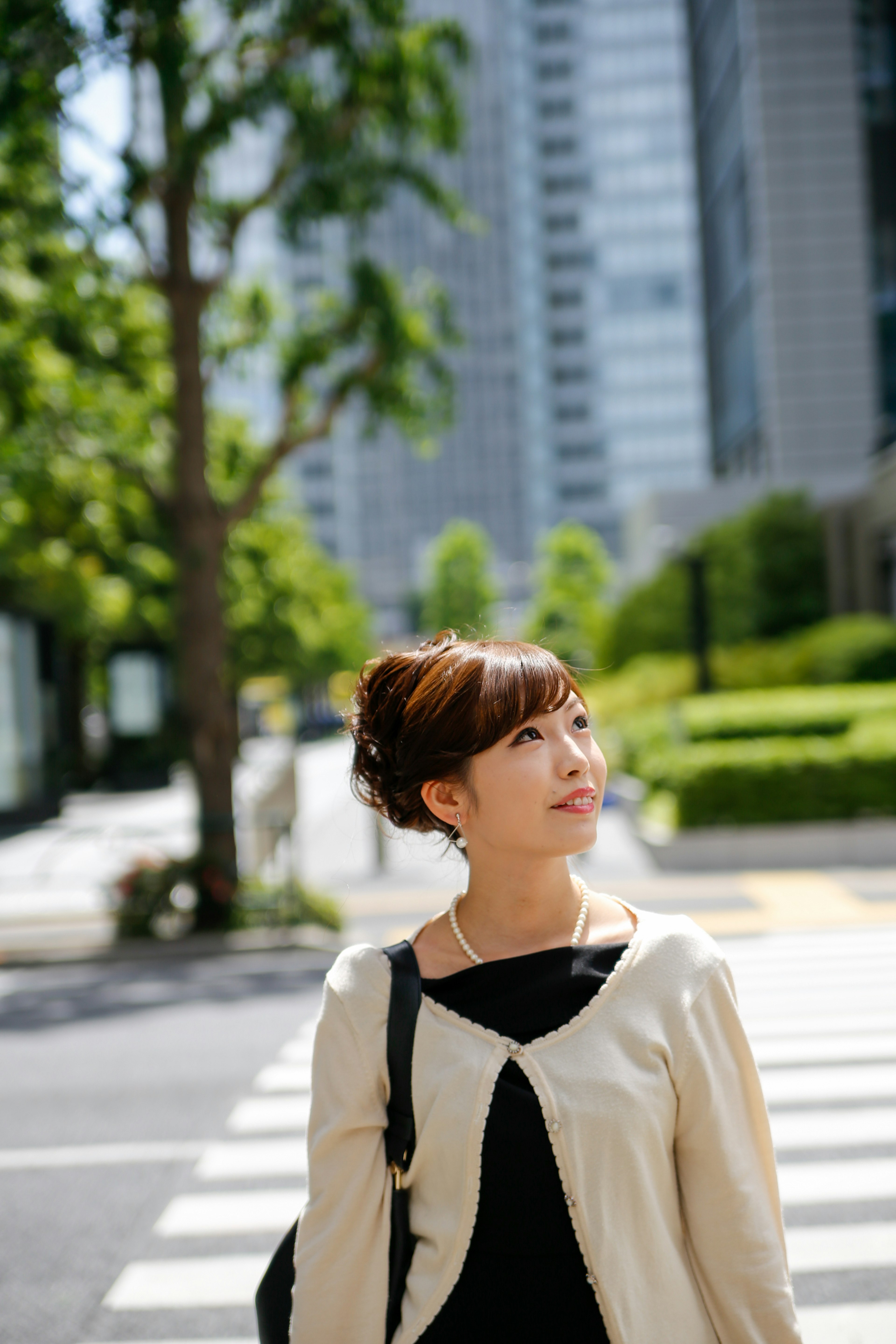 Woman walking on a city street with trees and skyscrapers in the background