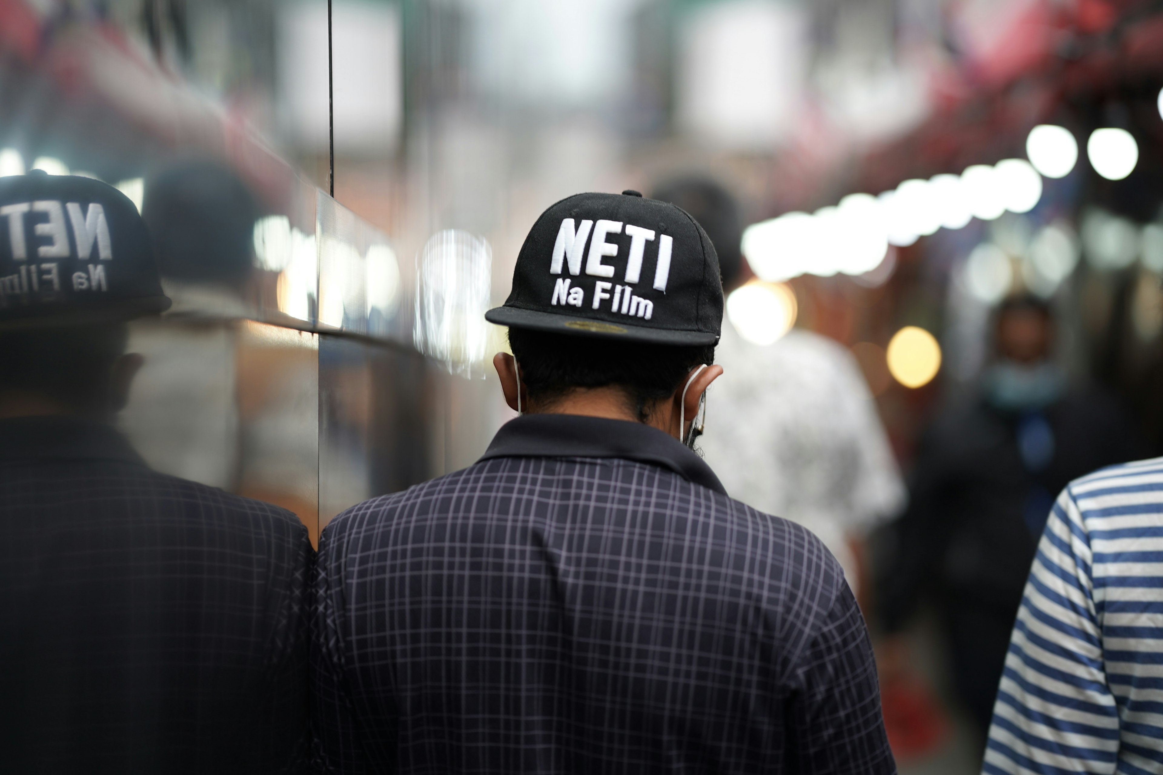 Un hombre con una gorra que dice NETI in Film visto desde atrás