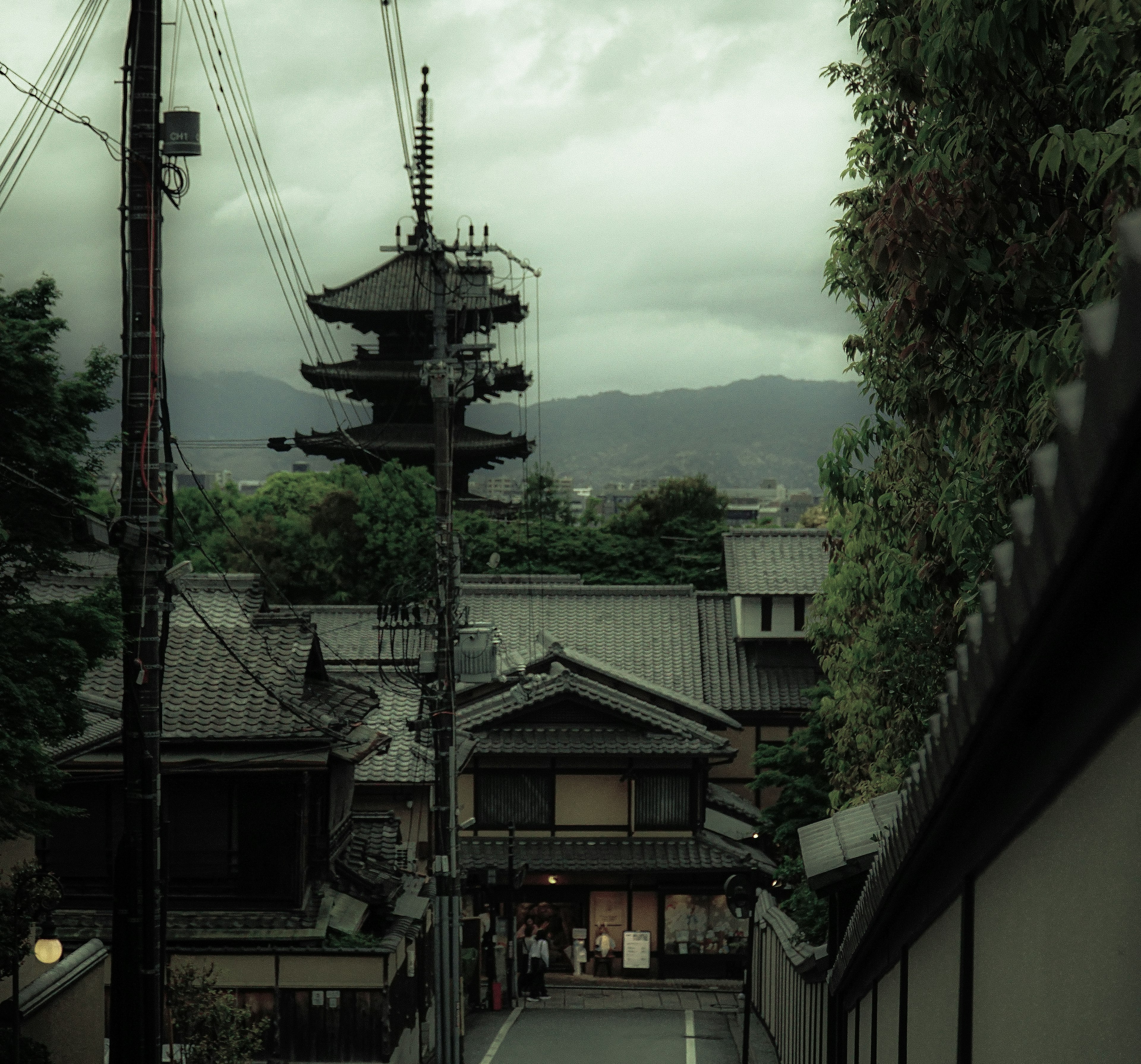 Traditional Japanese houses and a pagoda under a greenish sky