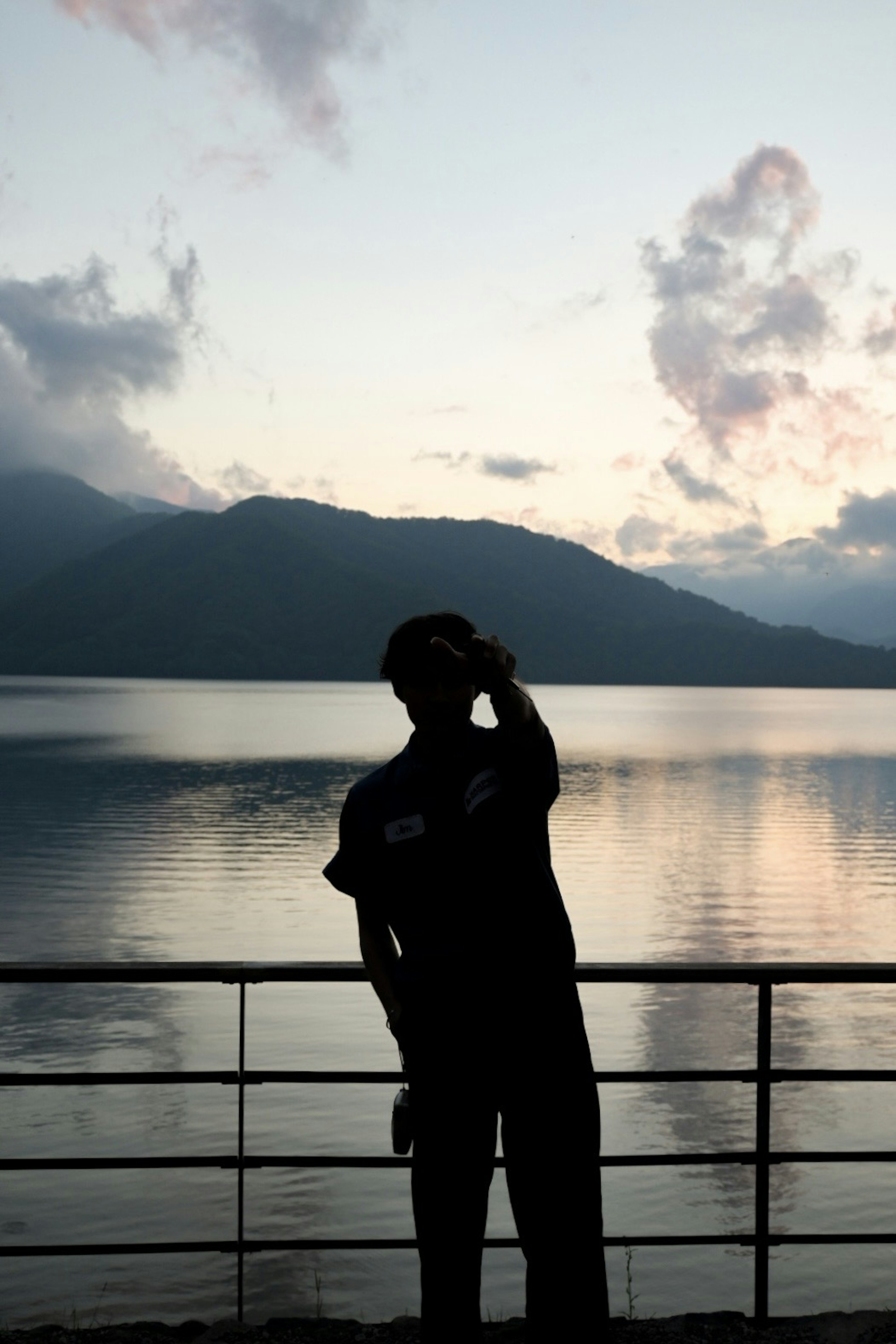 夕暮れ時の湖の前に立つ人影