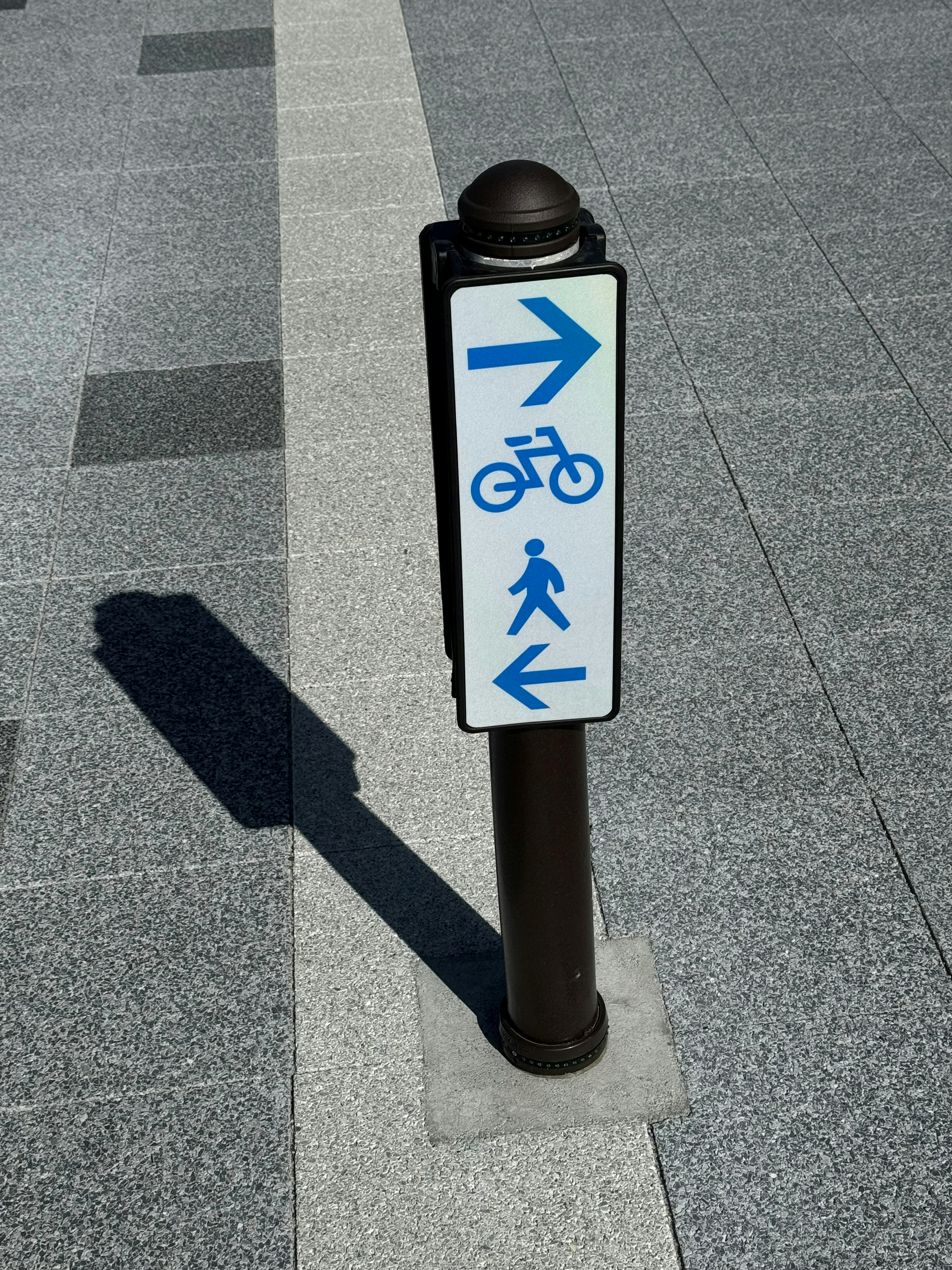 Panneau directionnel pour vélos et piétons sur un chemin pavé