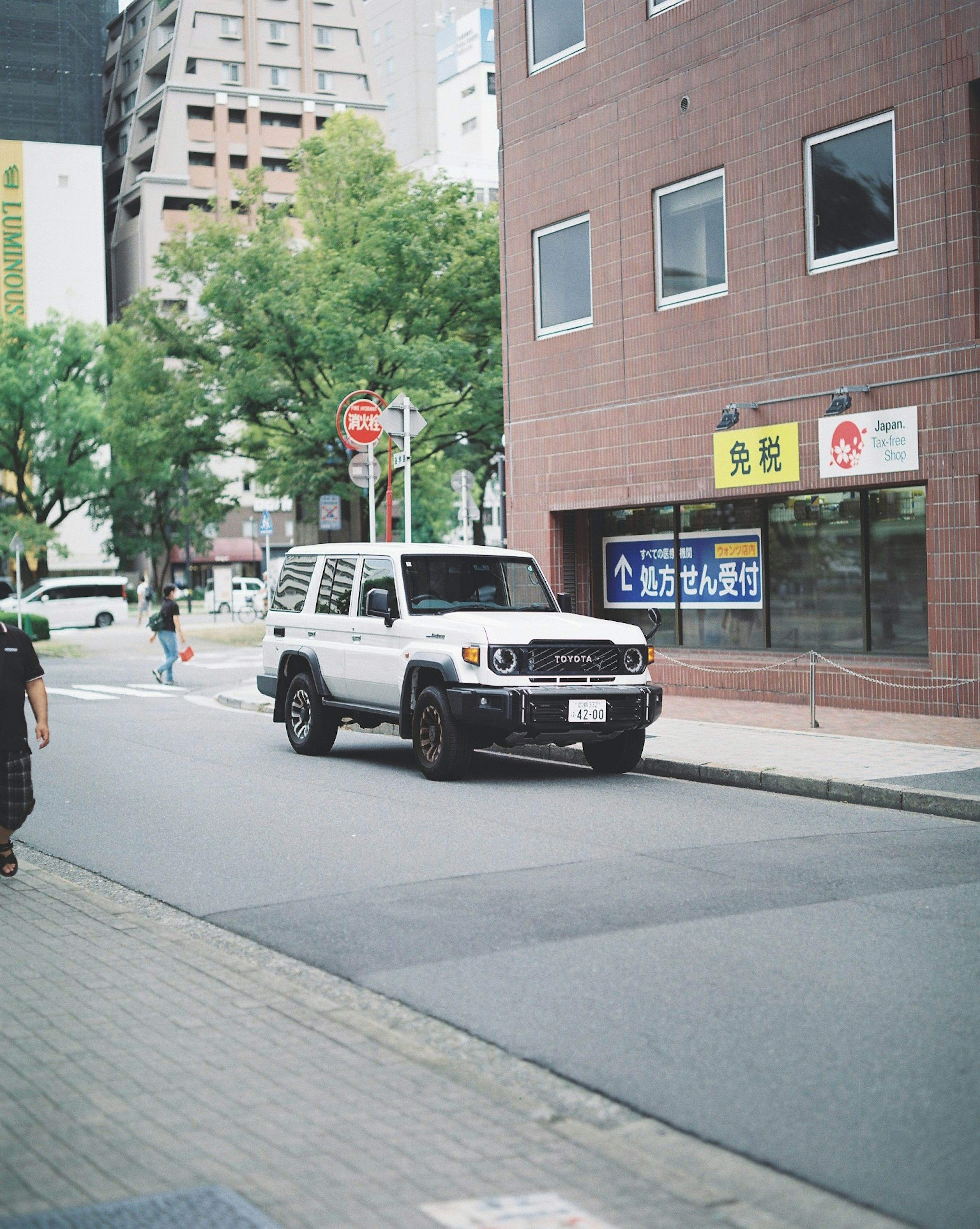 White SUV parked on an urban street with buildings and trees