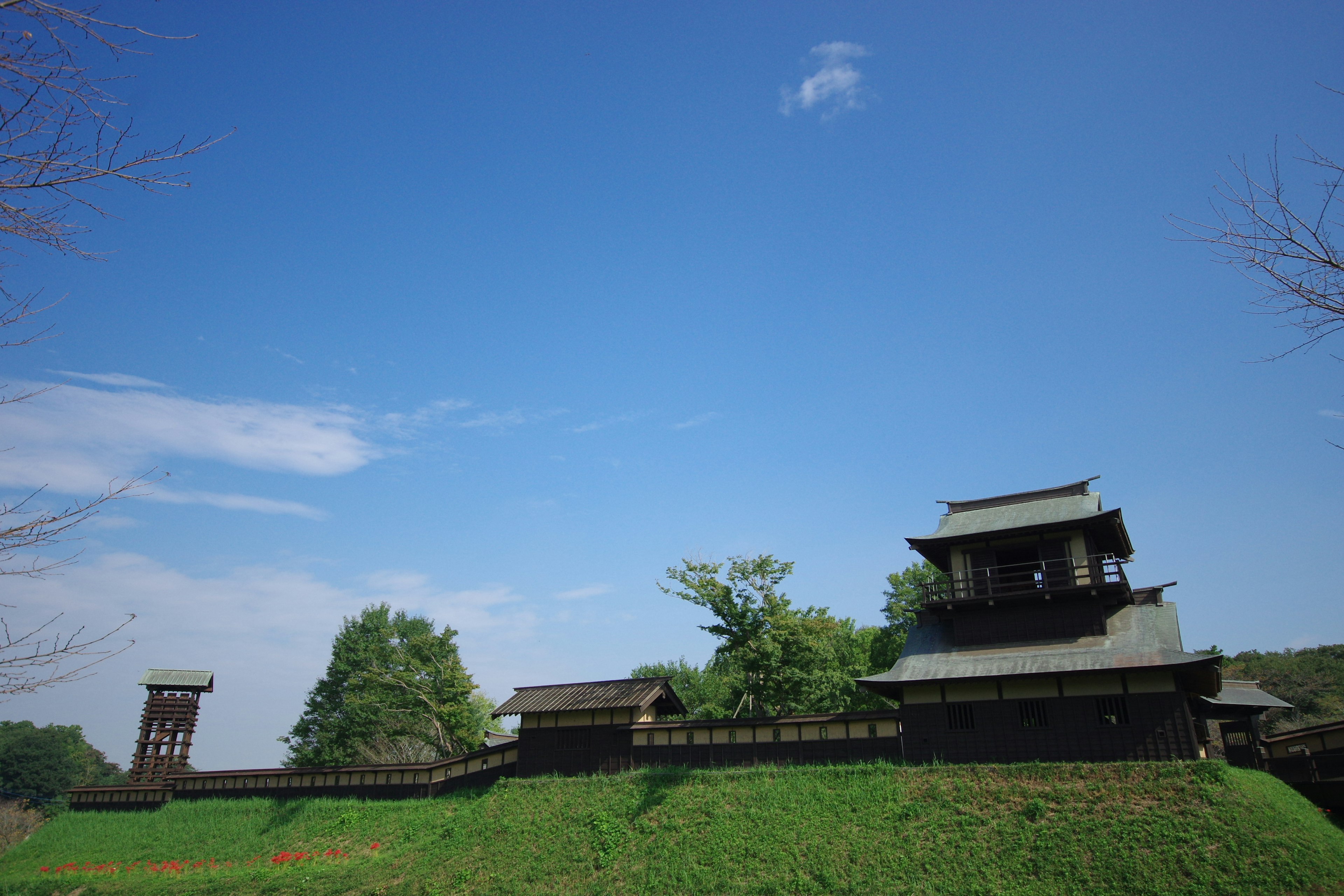 โครงสร้างปราสาทประวัติศาสตร์ใต้ท้องฟ้าสีฟ้าพร้อมเนินเขาสีเขียว