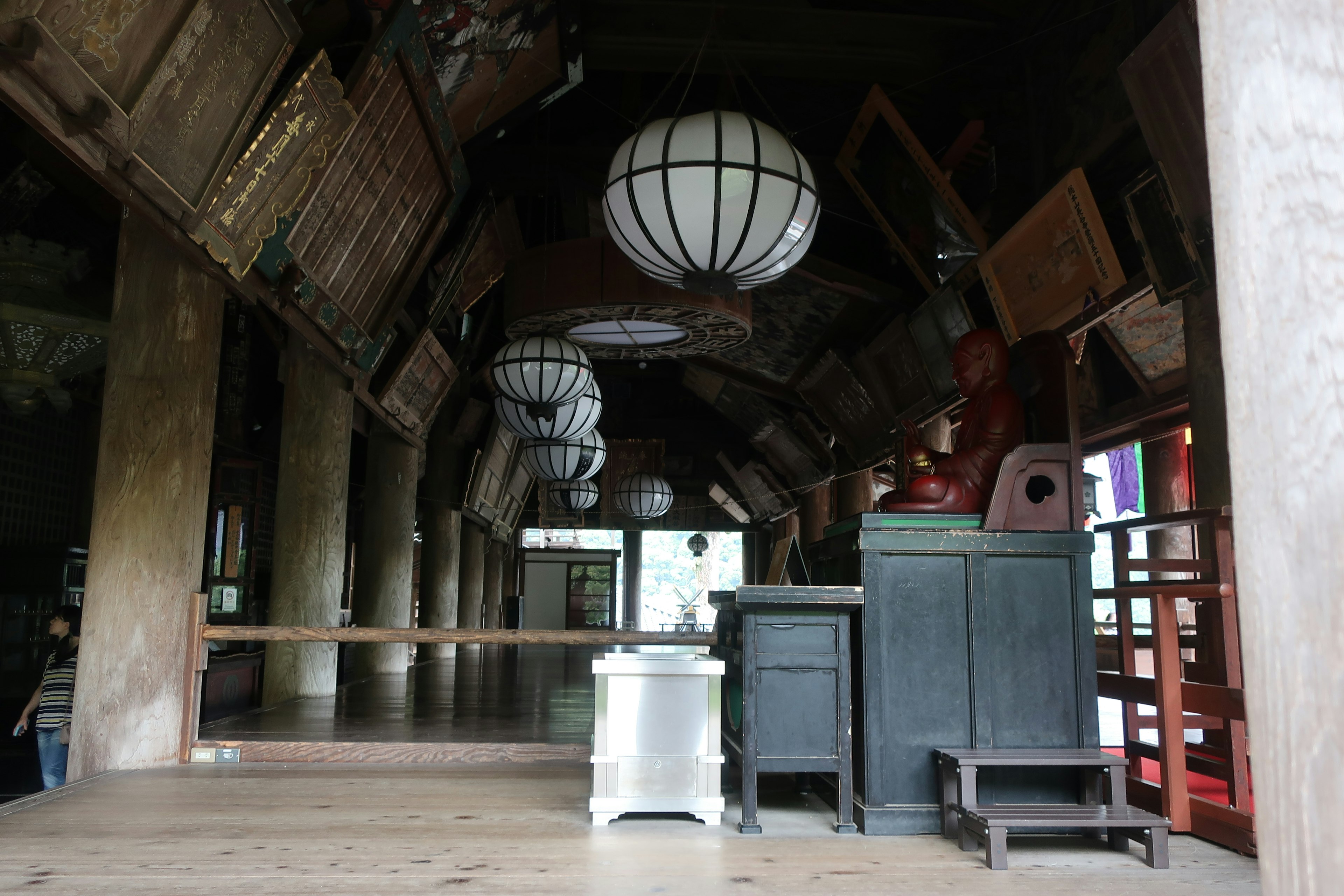 Vista interior de un antiguo edificio japonés con faroles colgantes y varios muebles