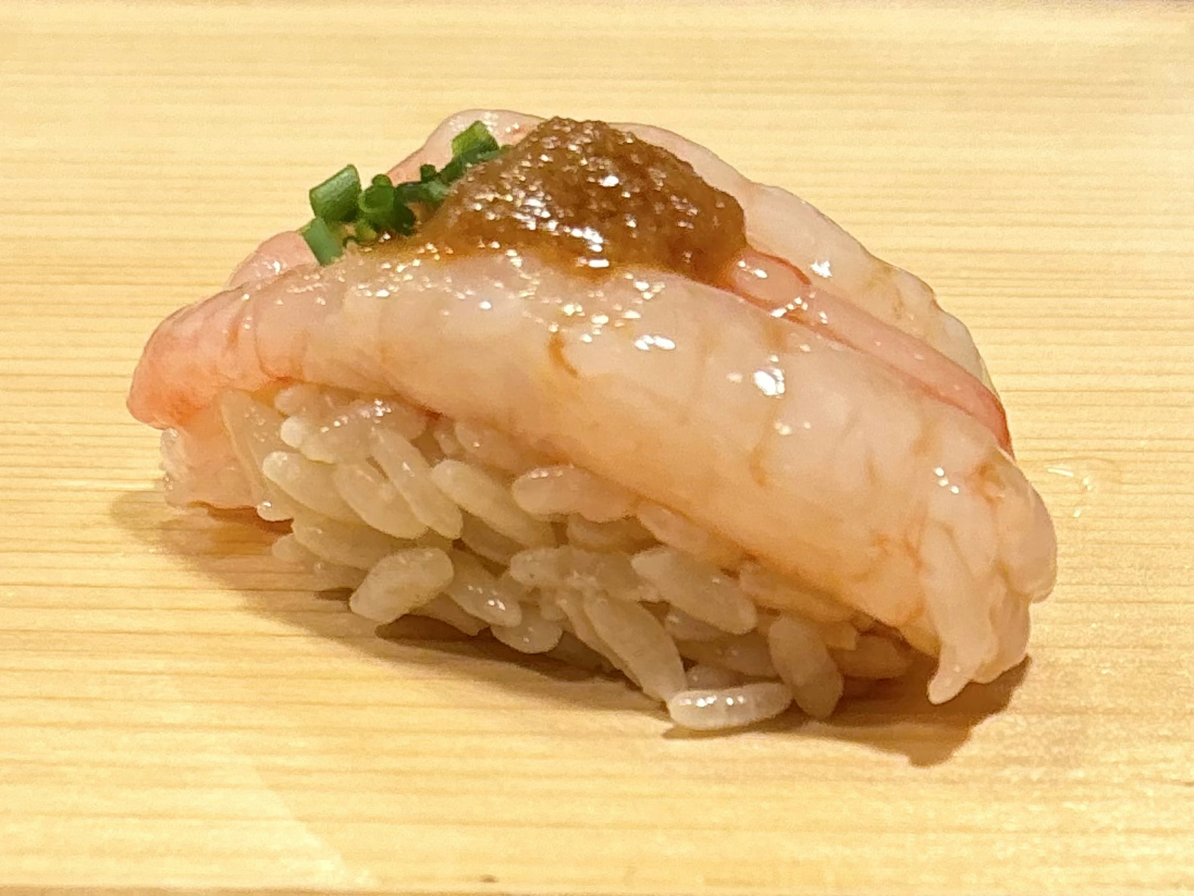 Un morceau de sushi garni de crevettes fraîches et d'une garniture verte