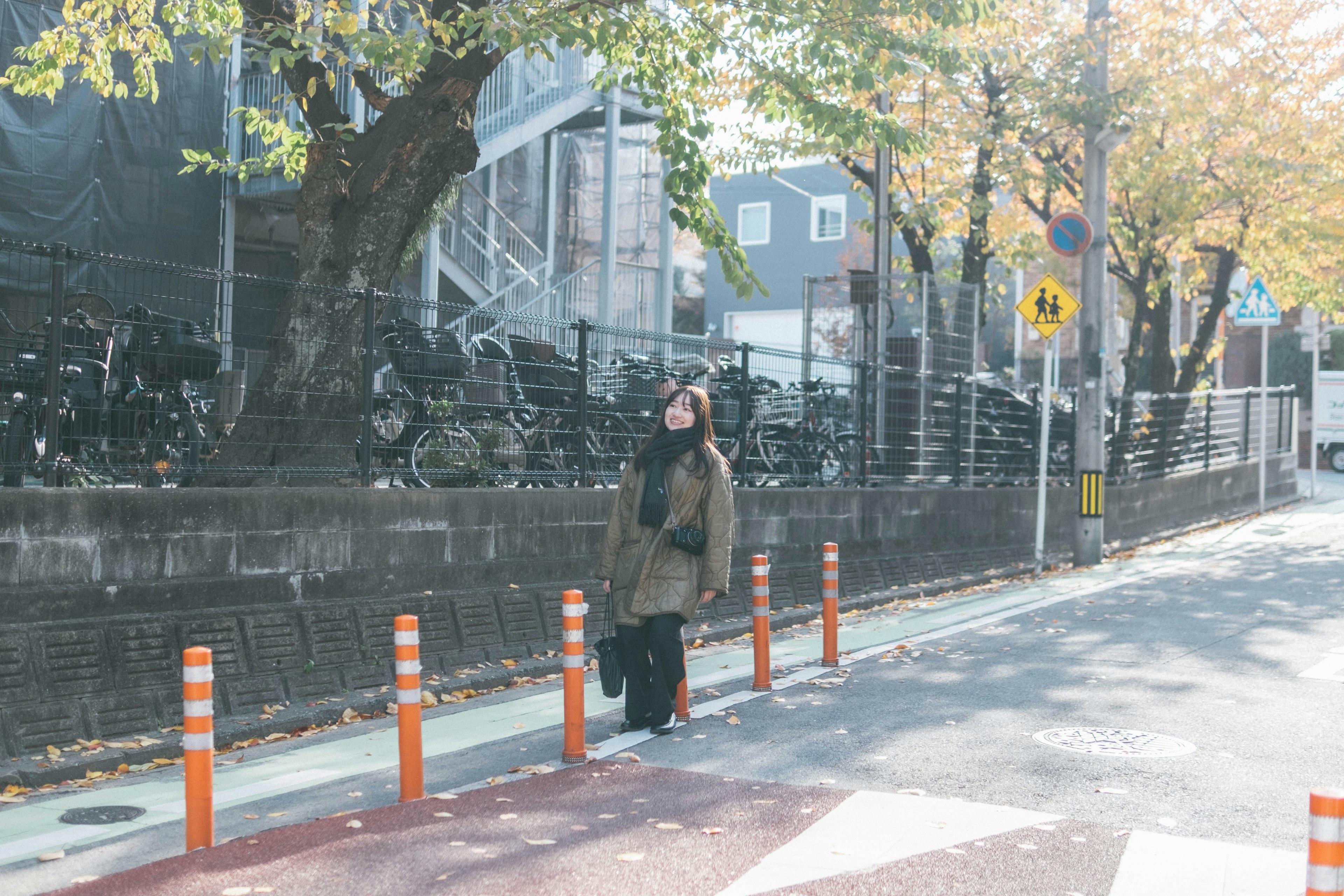 街中で立っている女性の姿 明るい日差しの中での秋の風景