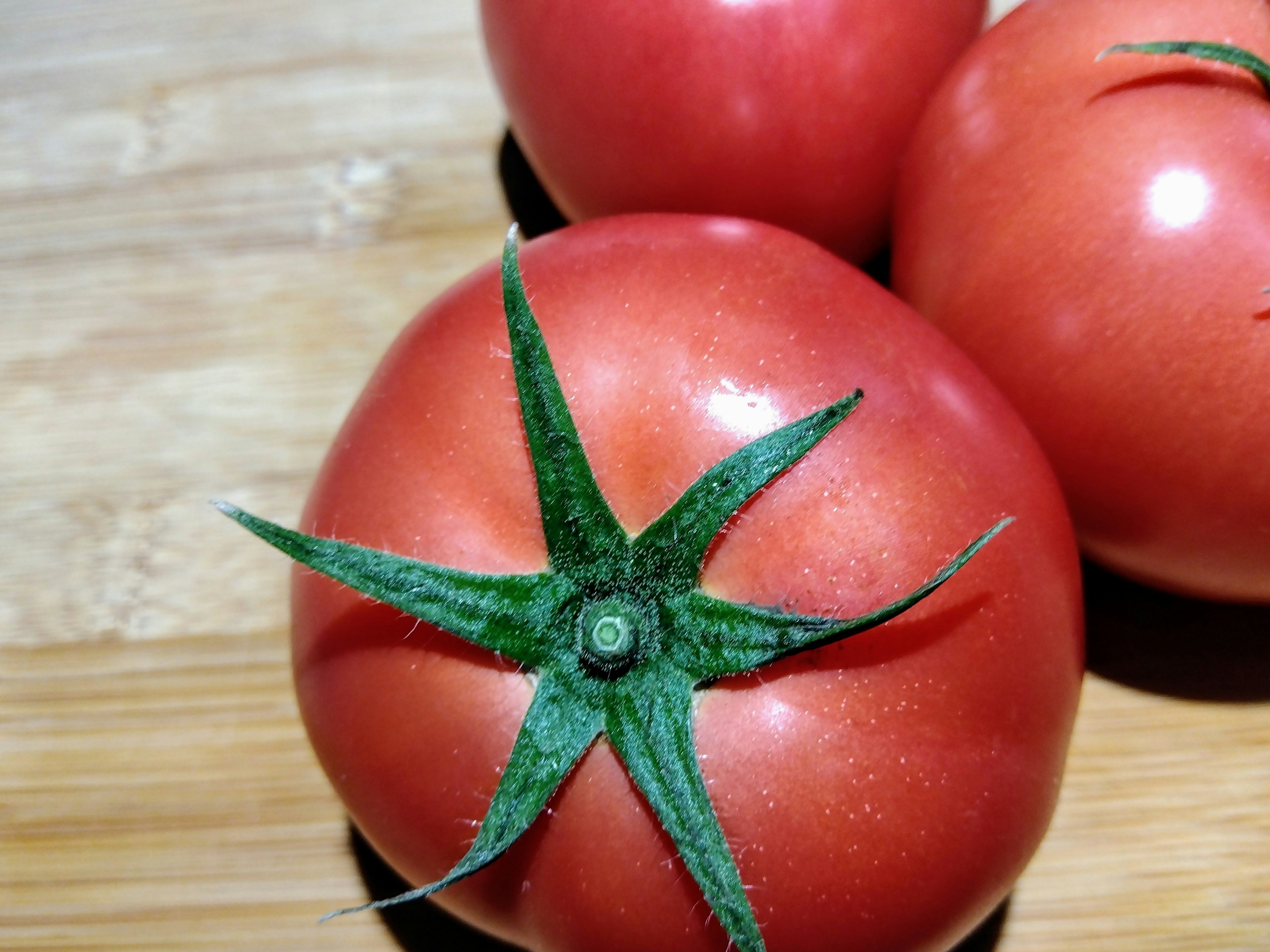 Close-up of a vibrant red tomato showcasing its green stem and leaves