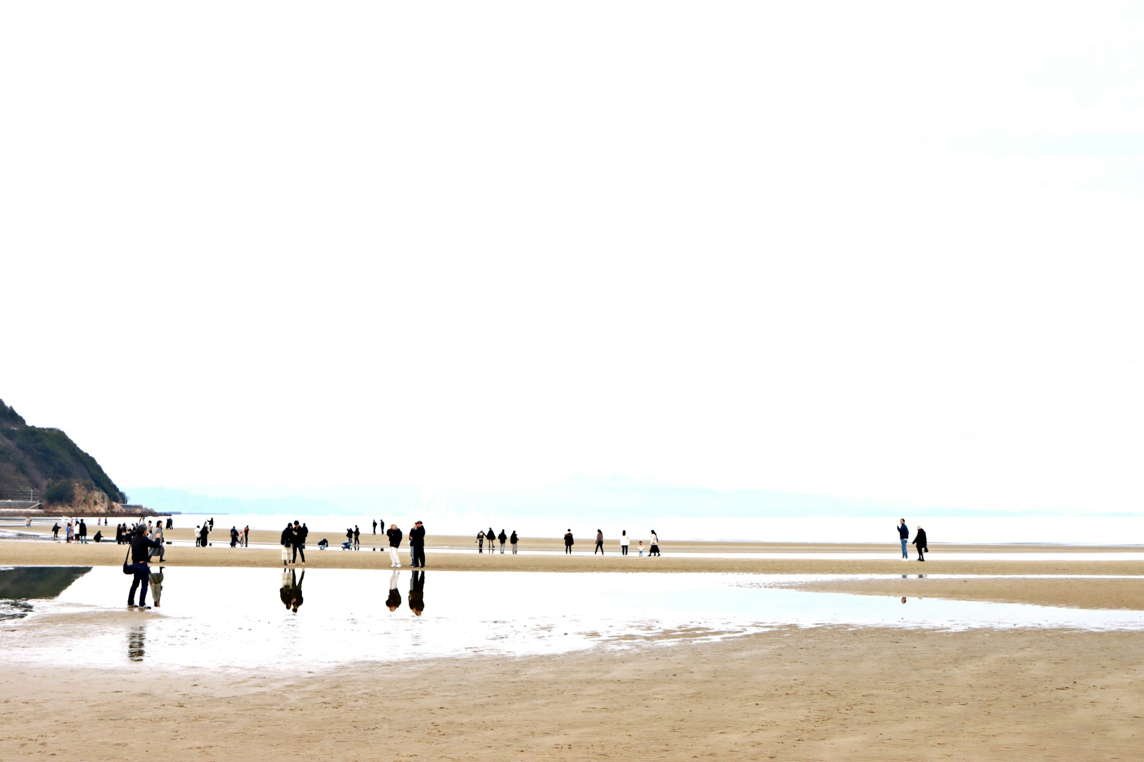 Plage de sable large avec des personnes éparpillées mer calme et ciel nuageux