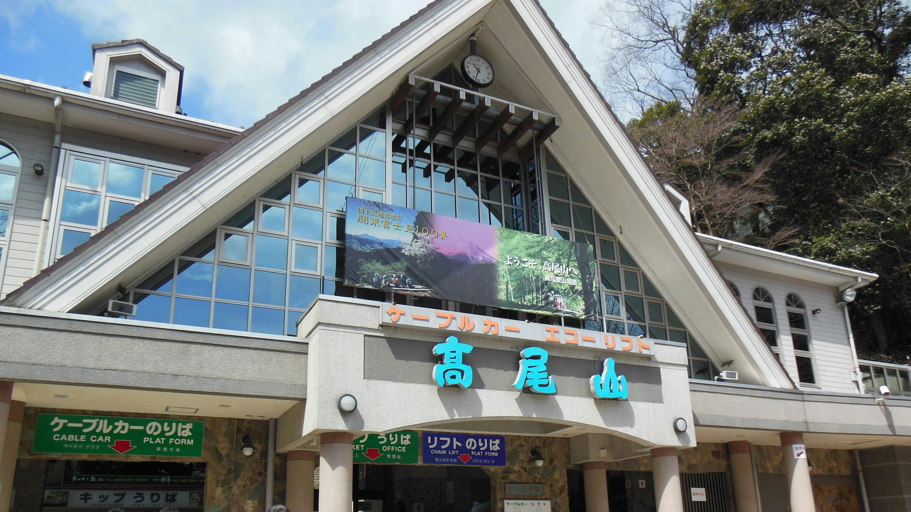 Exterior view of a station building with a large roof and digital signage