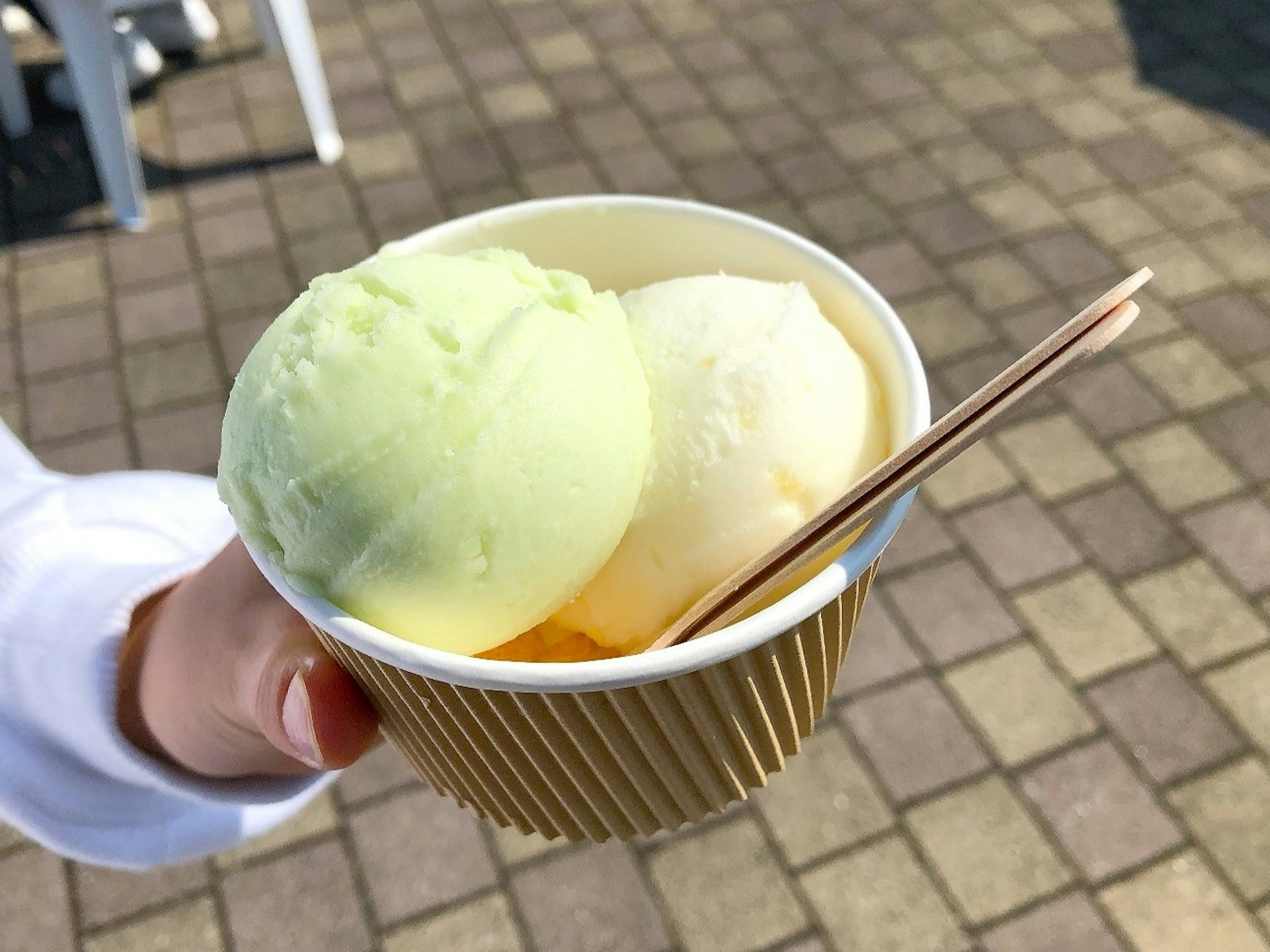 Eine Hand hält eine Tasse mit grünem und weißem Eis