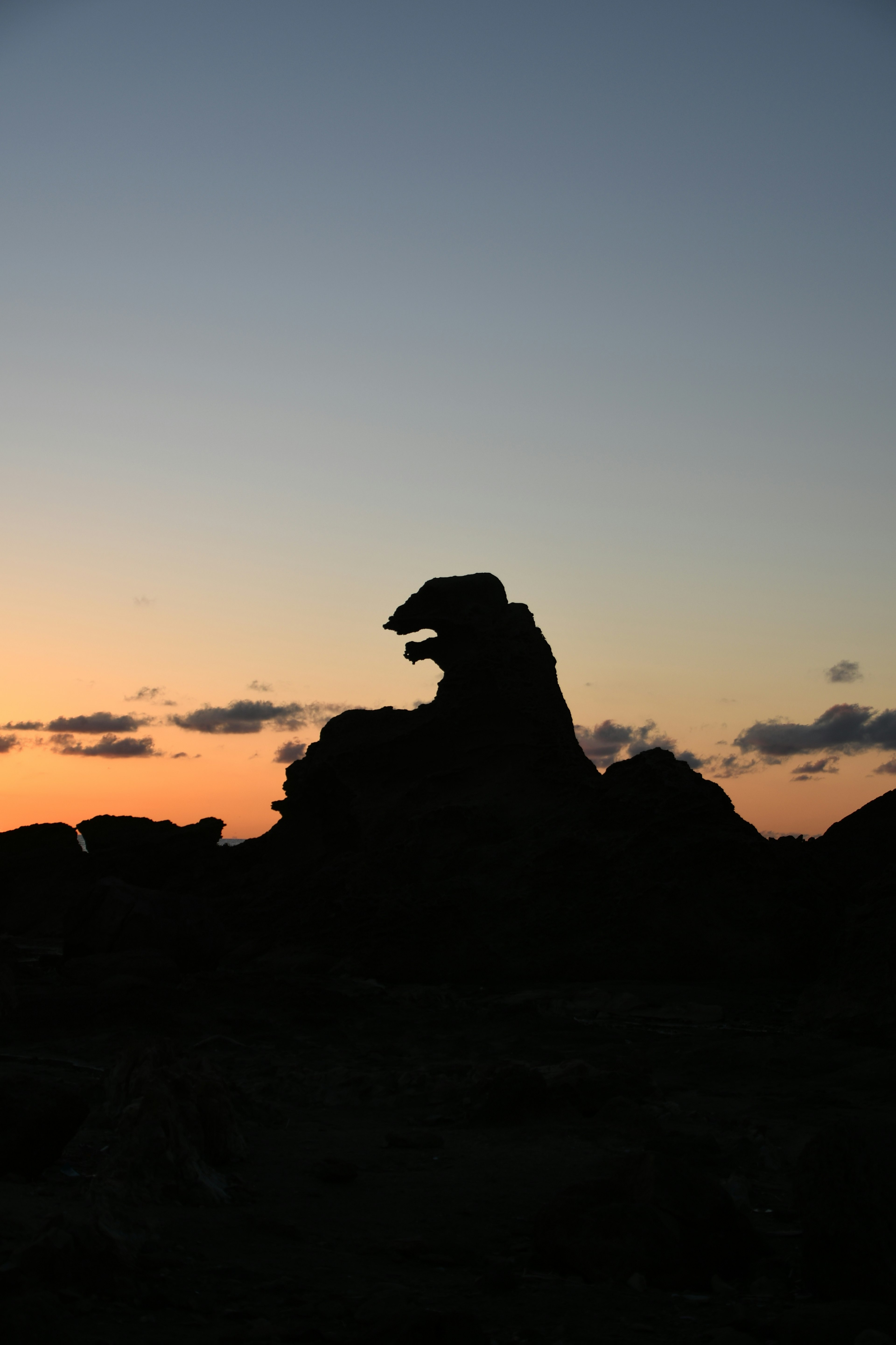 夕焼けの中に浮かび上がる岩のシルエットが特徴的な風景