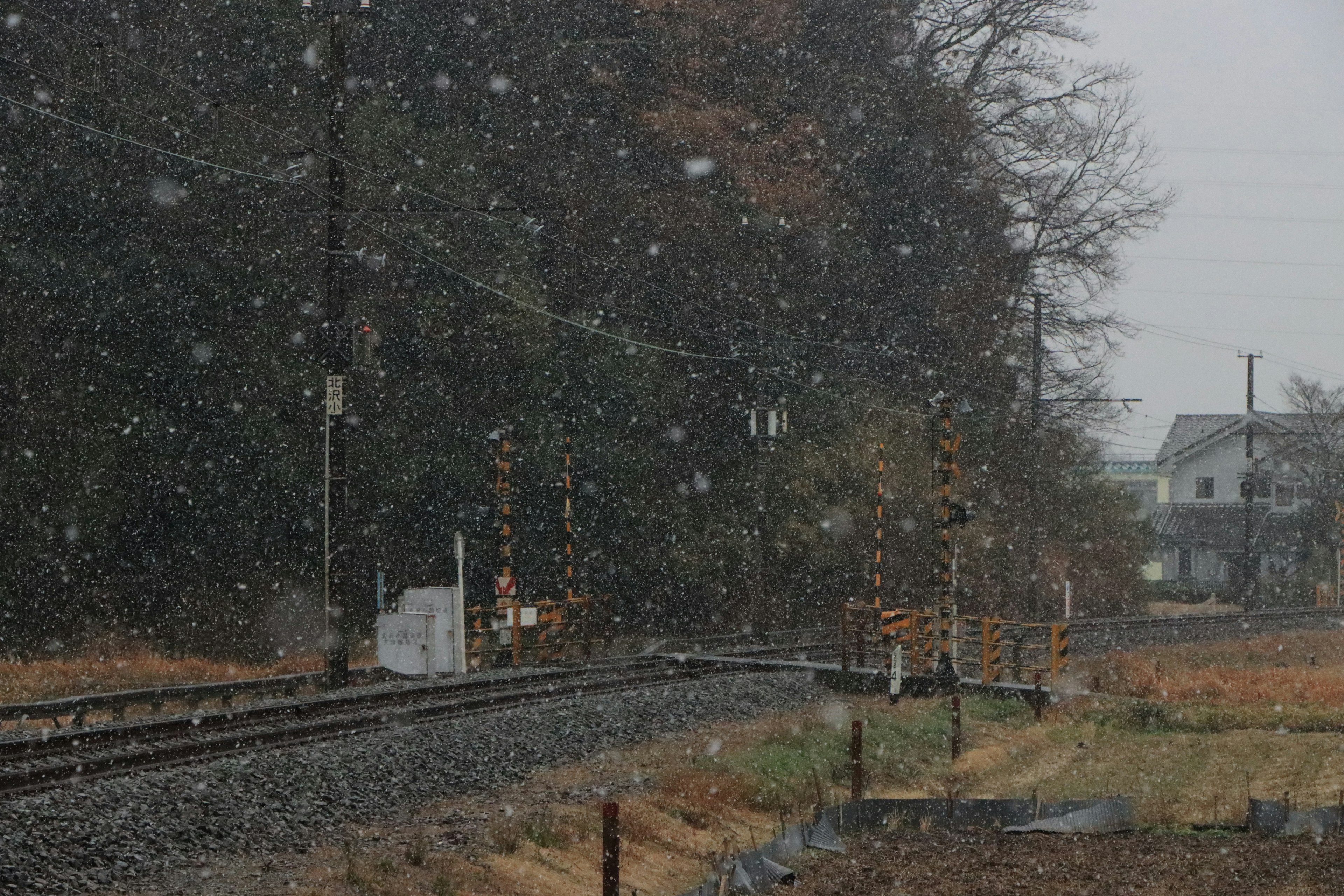 雪在铁路上落下，附近有房屋