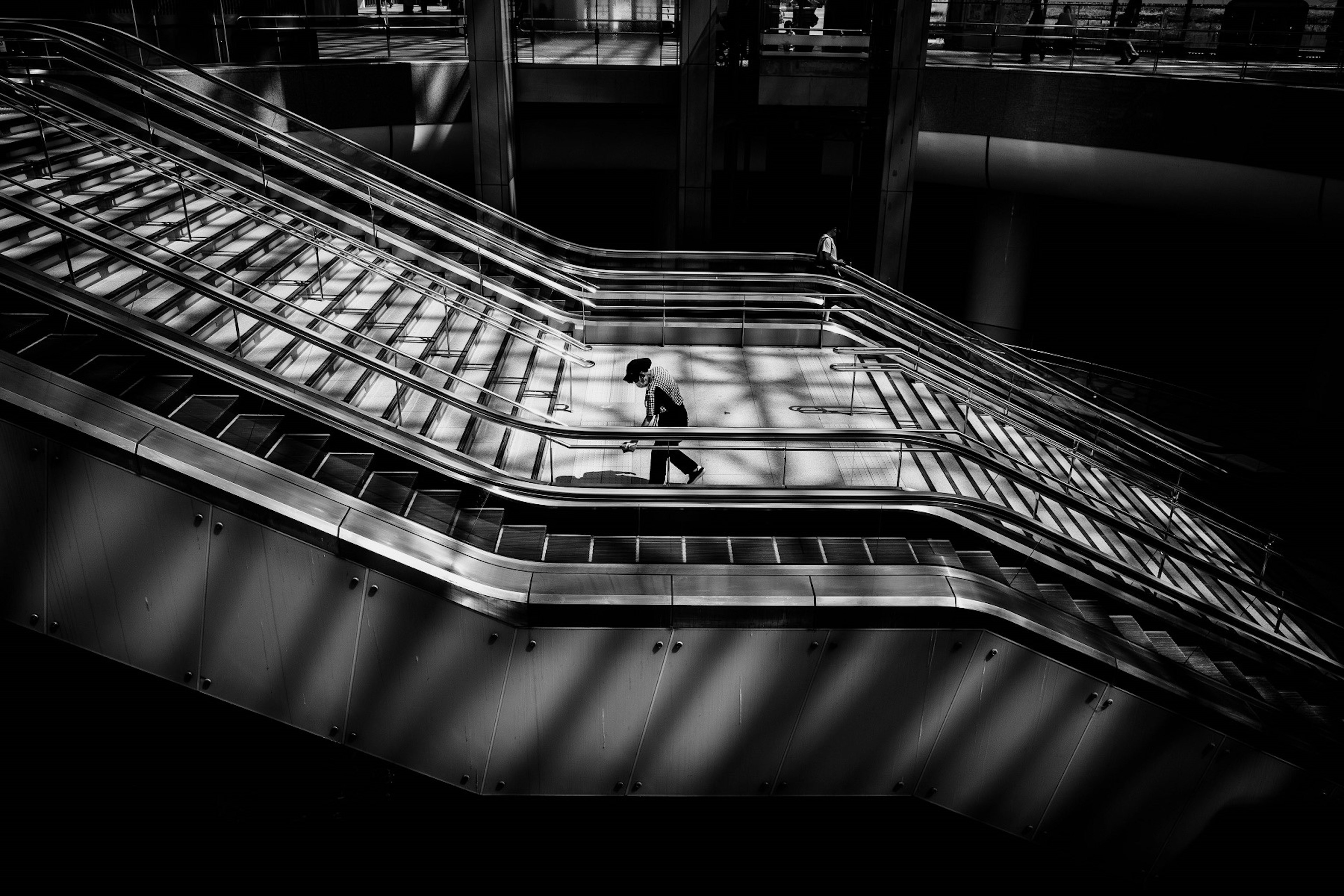 A monochrome photo featuring a person walking down stairs with striking contrasts of light and shadow