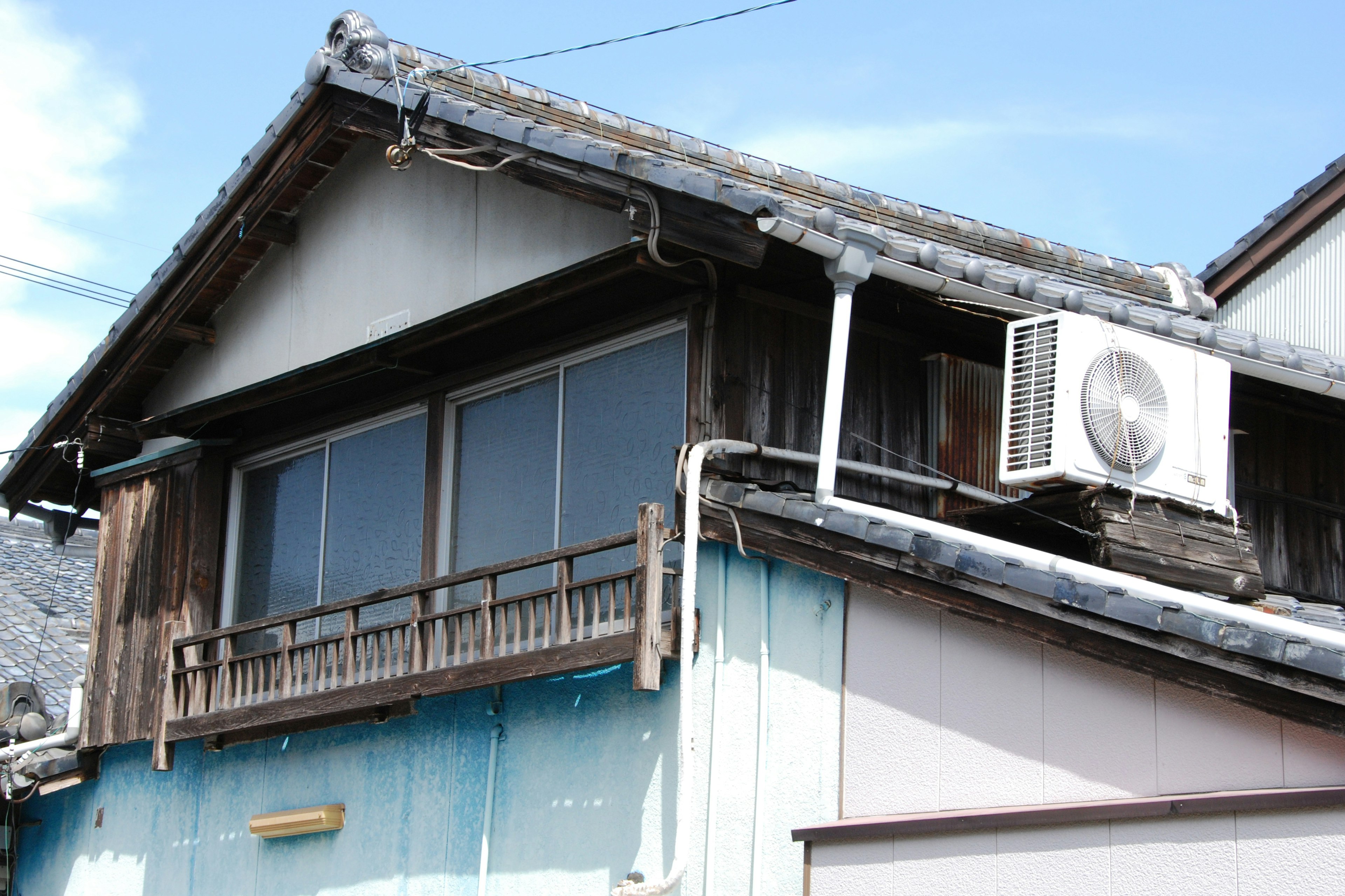 Exterior de una antigua casa japonesa con balcón de madera y aire acondicionado