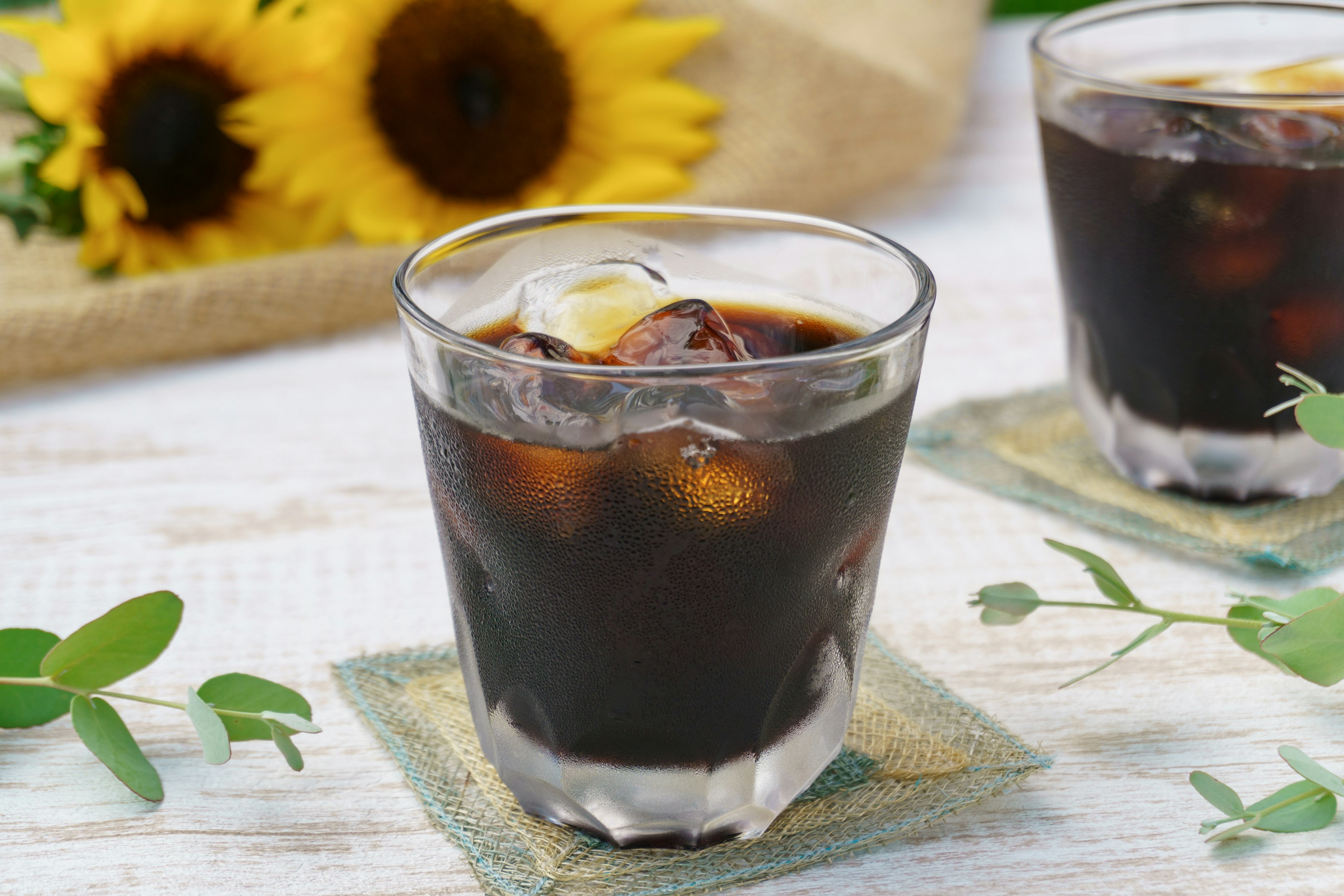 Vaso de café helado con girasoles al fondo