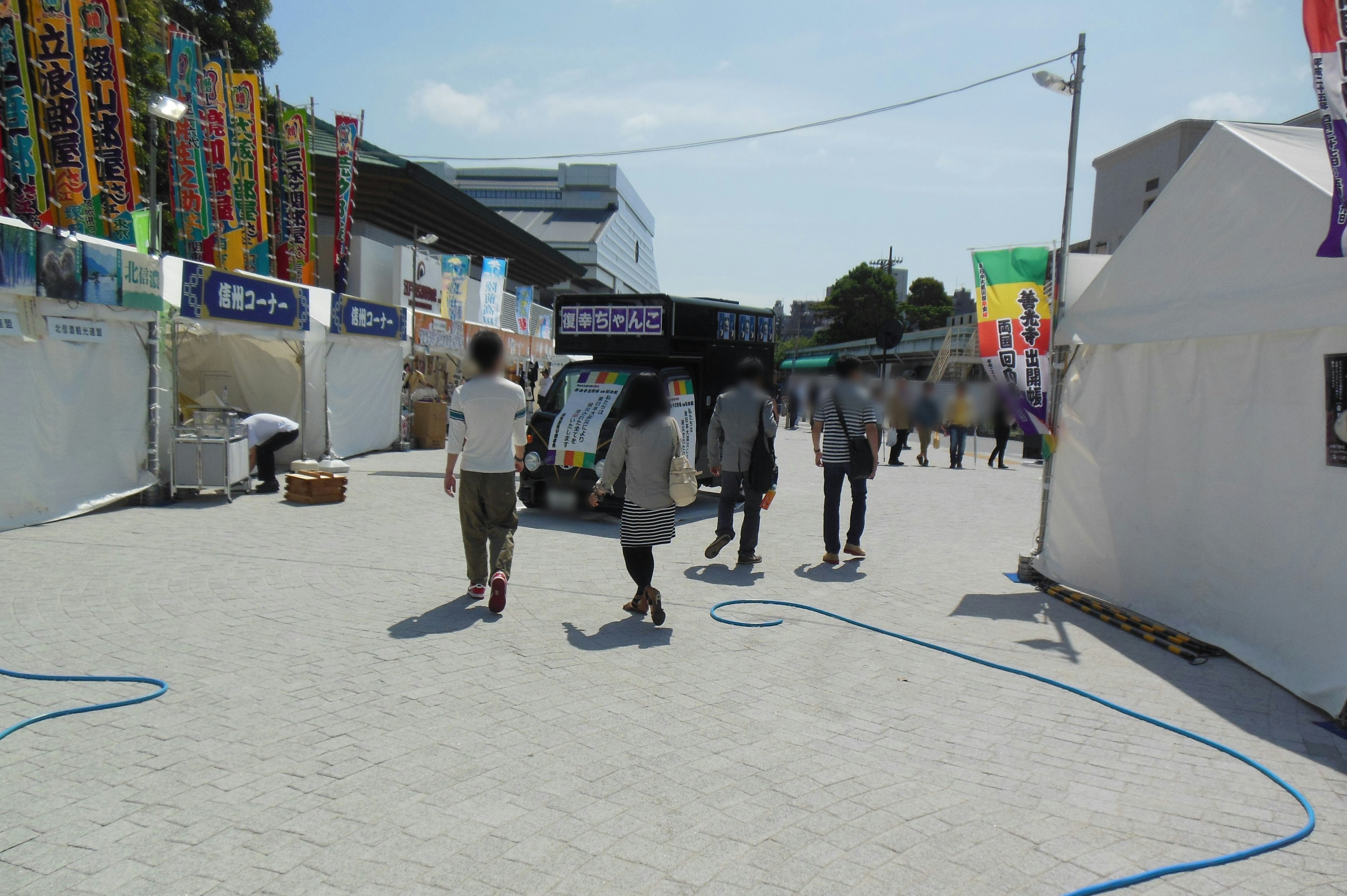 People walking in an event venue with white tents and colorful flags