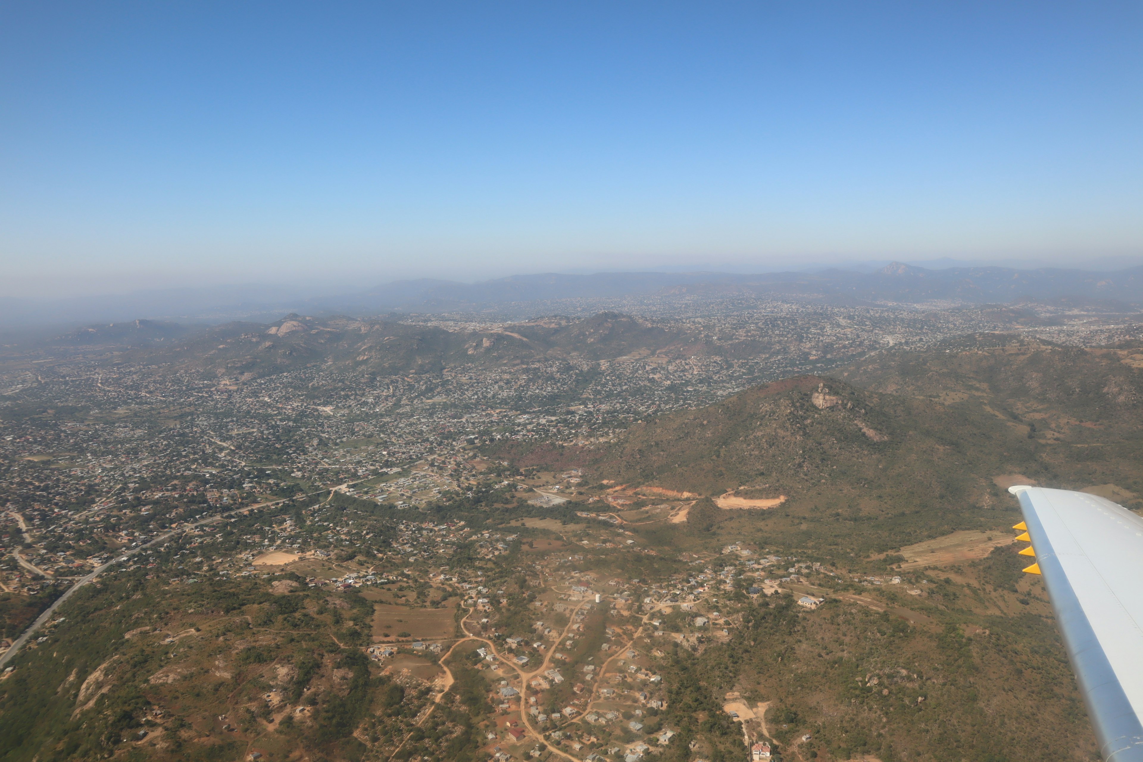 Luftaufnahme einer Stadt und Berge aus einem Flugzeugfenster