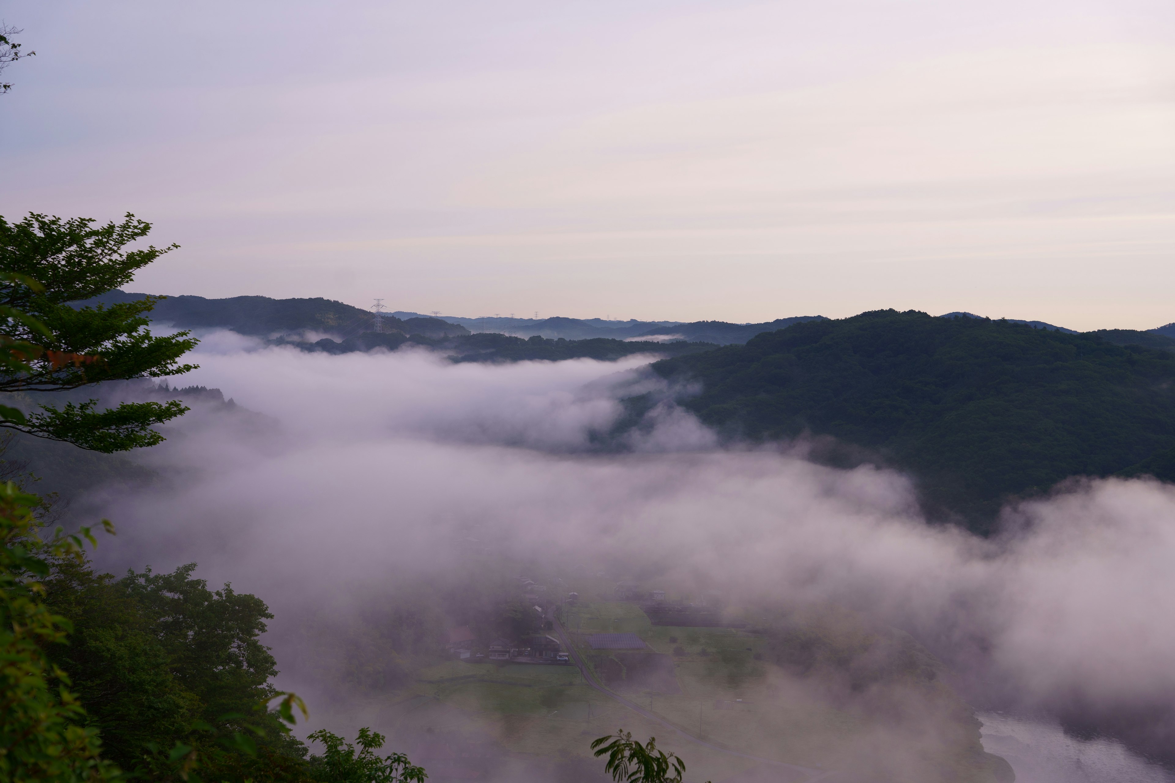 Paesaggio montano avvolto nella nebbia con tonalità morbide del cielo